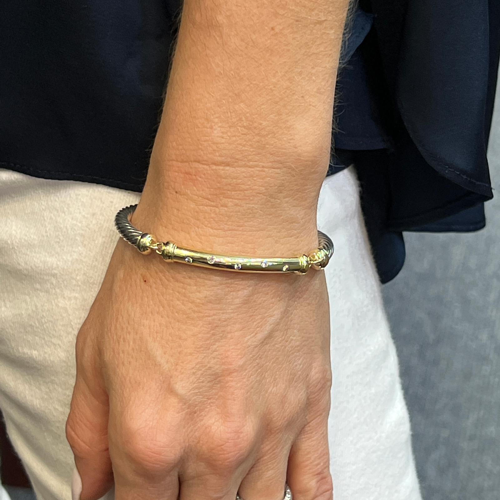 David Yurman Metro diamond cable bracelet fashioned in 14 karat yellow gold and sterling silver. The 5mm gold bar features 5 round brilliant cut diamonds weighing approximately .13 carat total weight. The bracelet features a lobster clasp, and