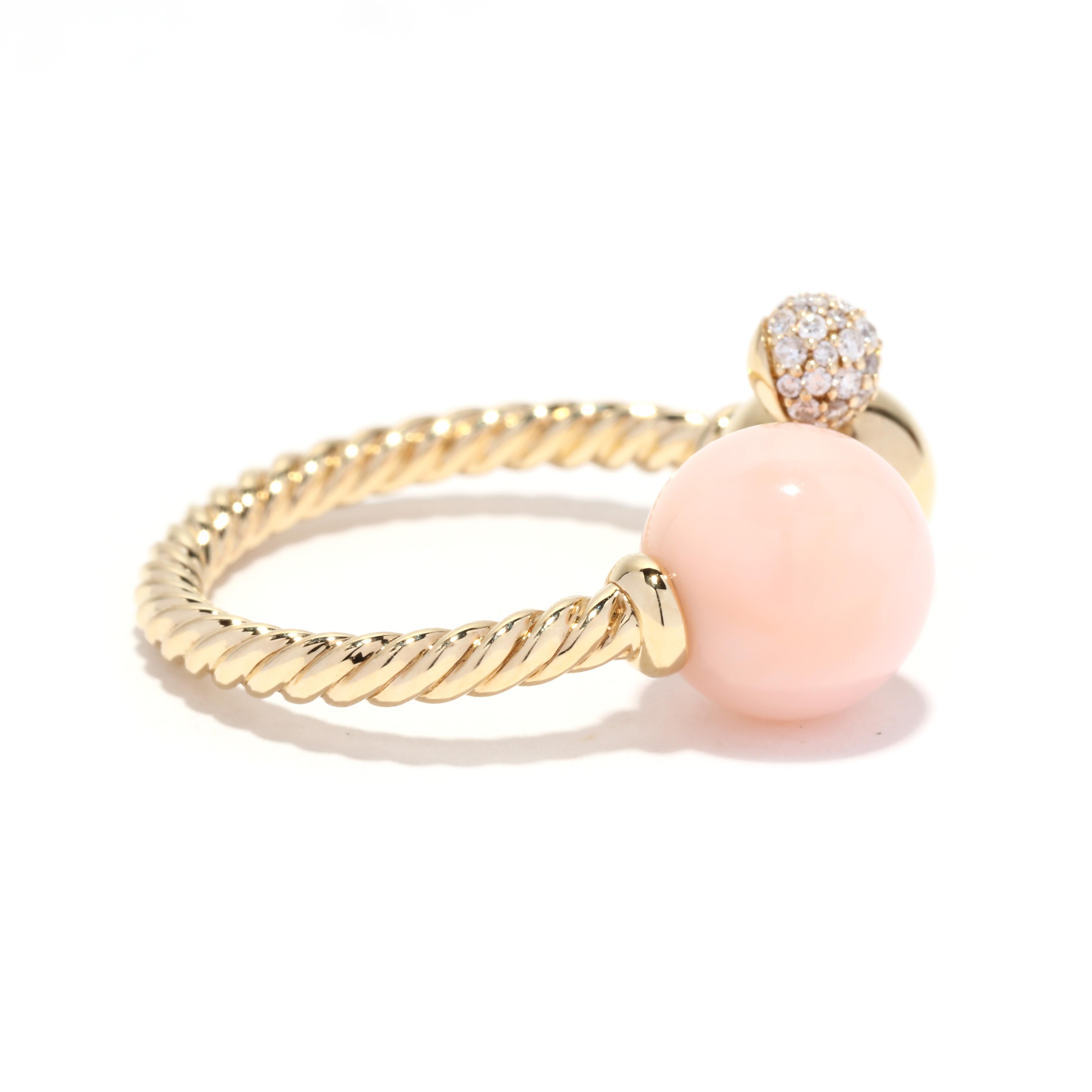 A David Yurman 18 karat yellow gold diamond and pink opal Solari ring. This cocktail ring features a cable motif band in an open design with a round pink opal bead end cap on one end and a gold bead with a pavé diamond ball weighing approximately