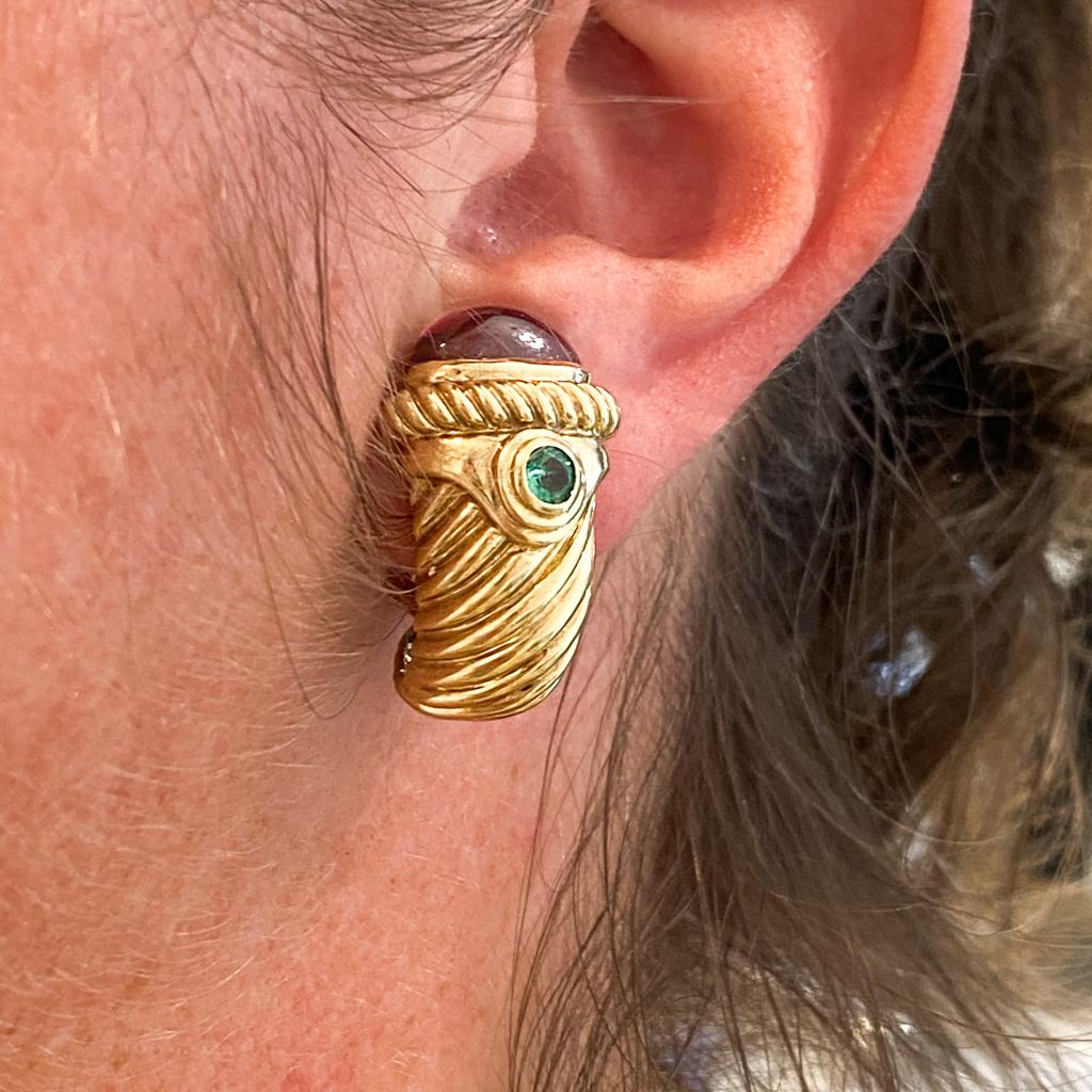 David Yurman classic styling shines bright in these 14 karat yellow gold half-hoops accented with gorgeous garnets and emeralds. The iconic cable twist design is beautifully sleek as it wraps across the hoops. Versatility is the key to these