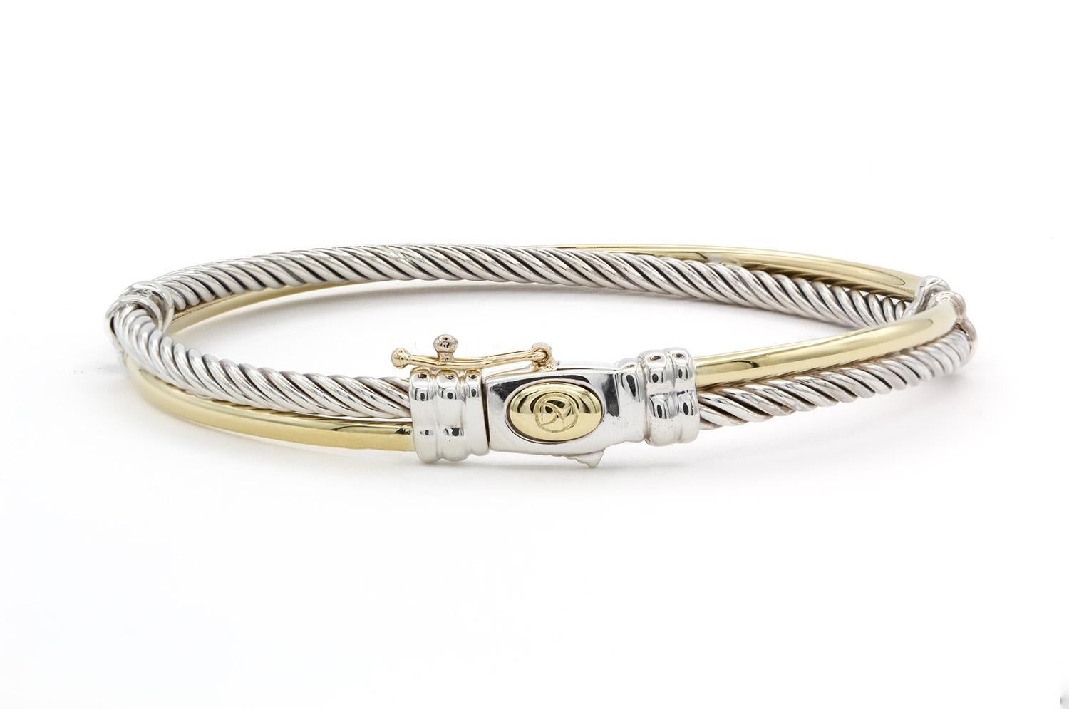 We are pleased to offer this David Yurman Linked Crossover Cable Bracelet. This bracelet features David Yurmans classic cable design with a twist! Fashioned from sterling silver & 18k yellow gold the bracelet measures 5mm wide and will fit up to a