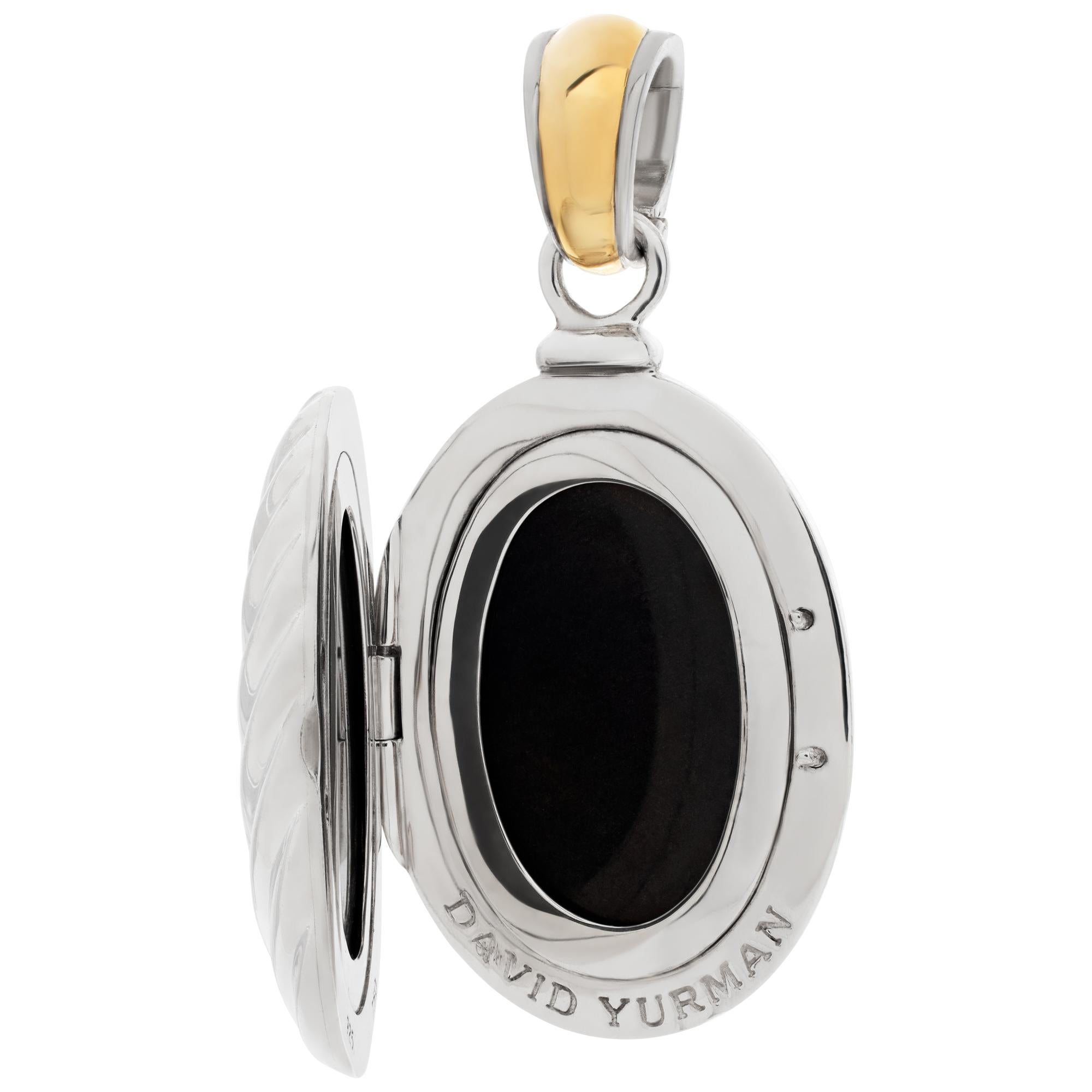 David Yurman locket pendant in 925 sterling silver and 18k yellow gold with cable pattern with hinged bale. Lenght is 57 mm and picture opening is 24 mm x 16 mm.
