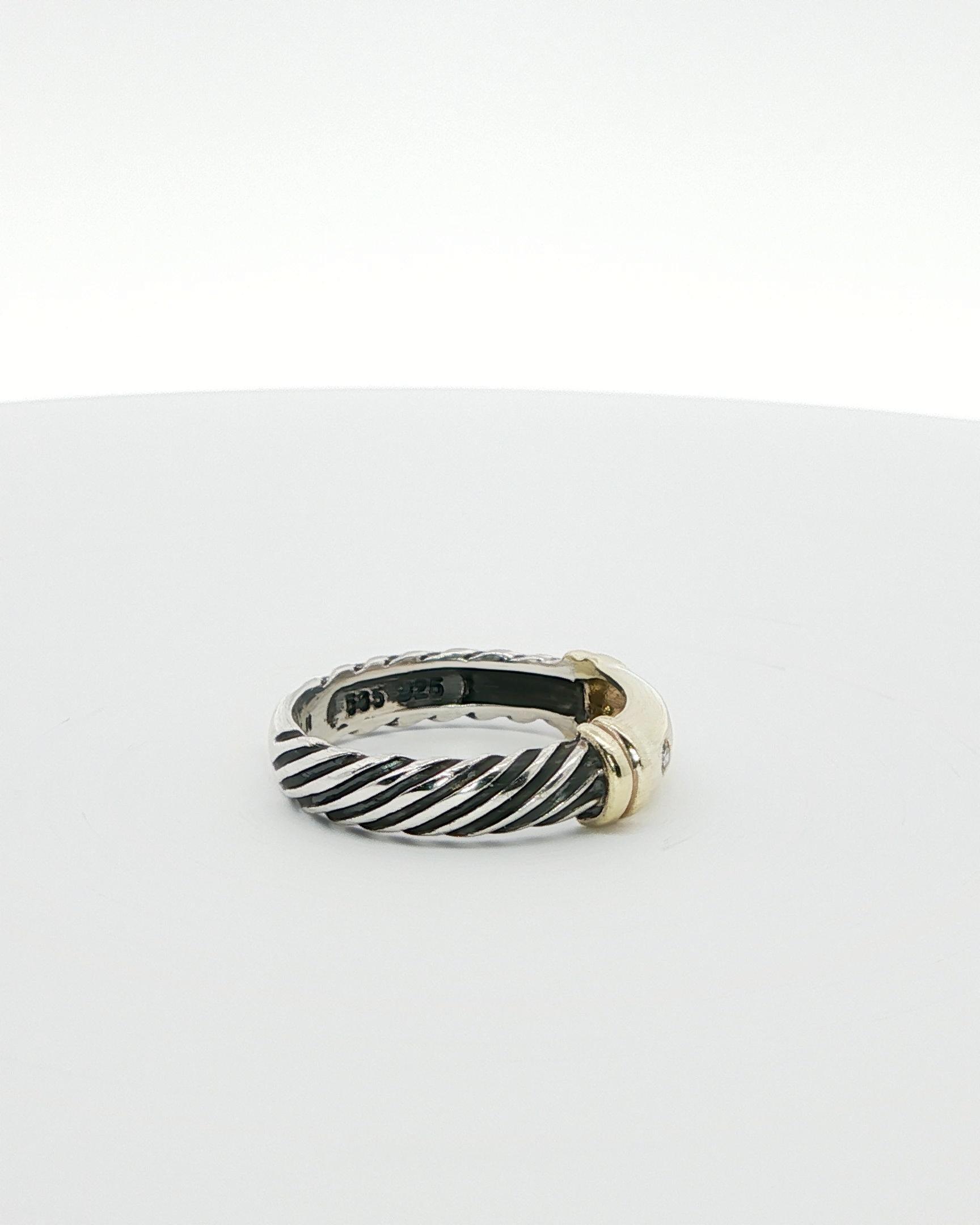 This David Yurman ring features a row of three round brilliant-cut natural diamonds in a classic two-tone metal cable ring synonymous with the Yurman brand.  The band's design is classically elegant and timeless, , making it a perfect addition to