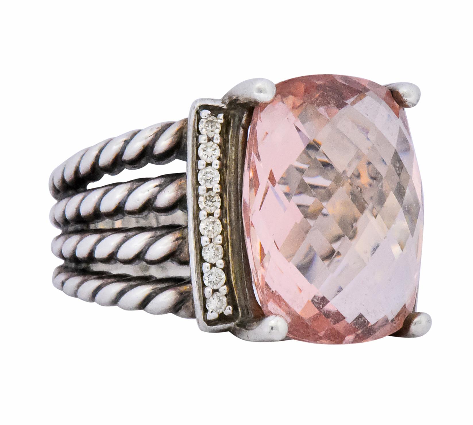 Centering a cushion shaped, checkerboard cut morganite, measuring approximately 16.0 x 12.0 x 7.3 mm, light orangey pink 

Flanked by round brilliant cut diamonds, weighing approximately 0.16 carat total, eye-clean and white

With a spilt multi