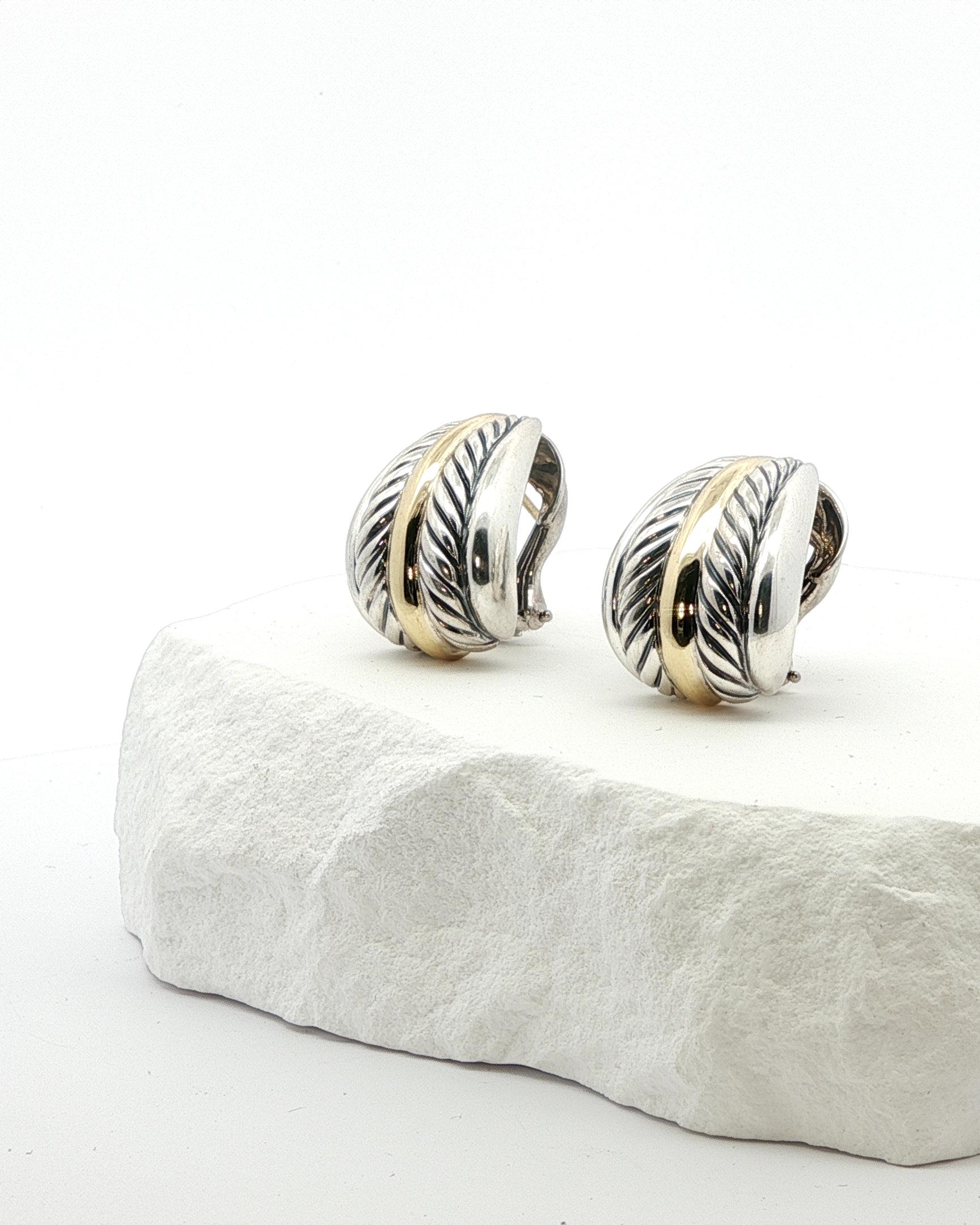 Eleva il tuo stile con questi intramontabili orecchini a cerchio in argento David Yurman, impreziositi da bande in oro giallo 14 carati. Gli orecchini vantano un design strutturato che aggiunge profondità e dimensione alla classica silhouette a