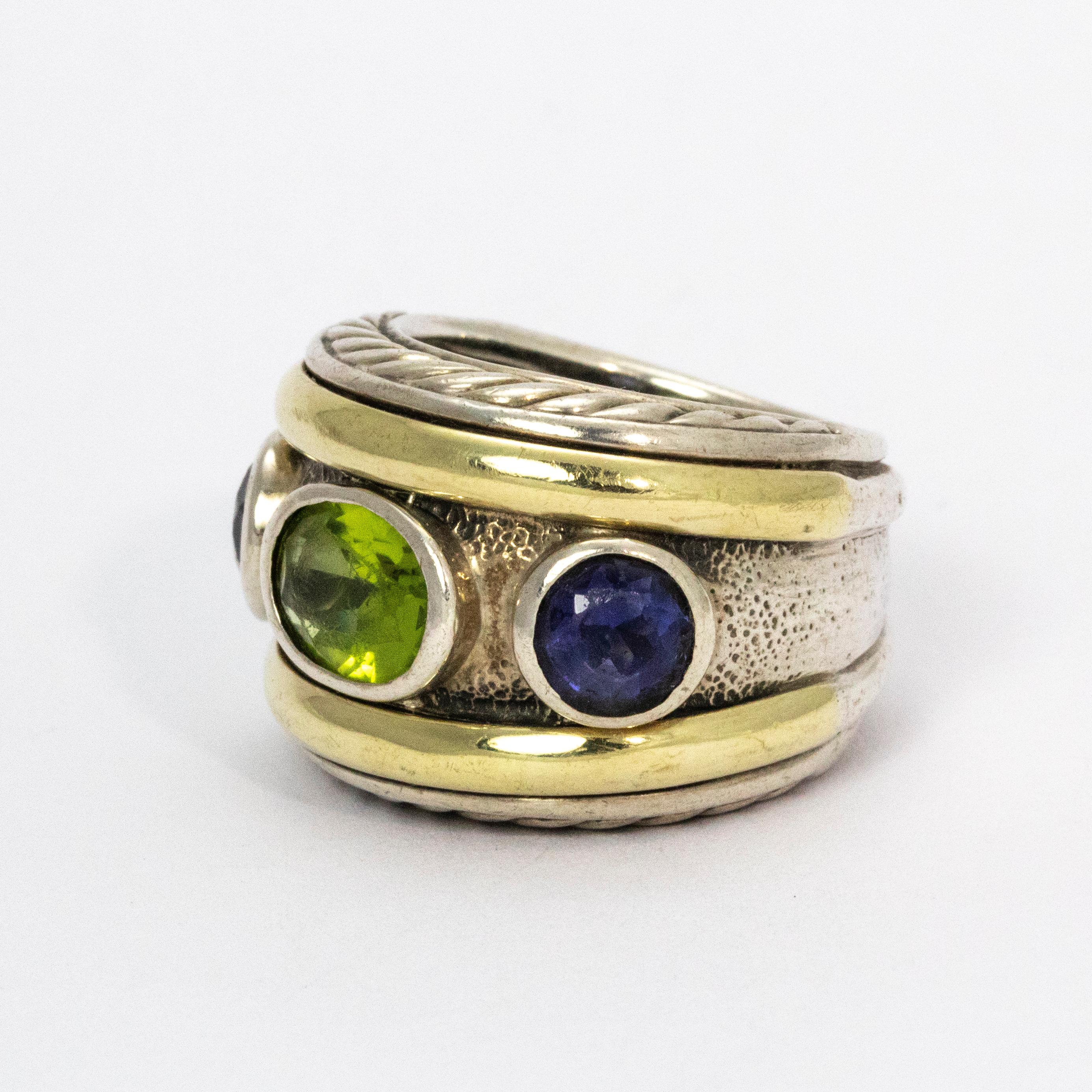 David Yurman wide silver band with decorative 14k gold detail finished beautifully with an oval peridot and two round amethyst side stones.

Ring Size: M or 6