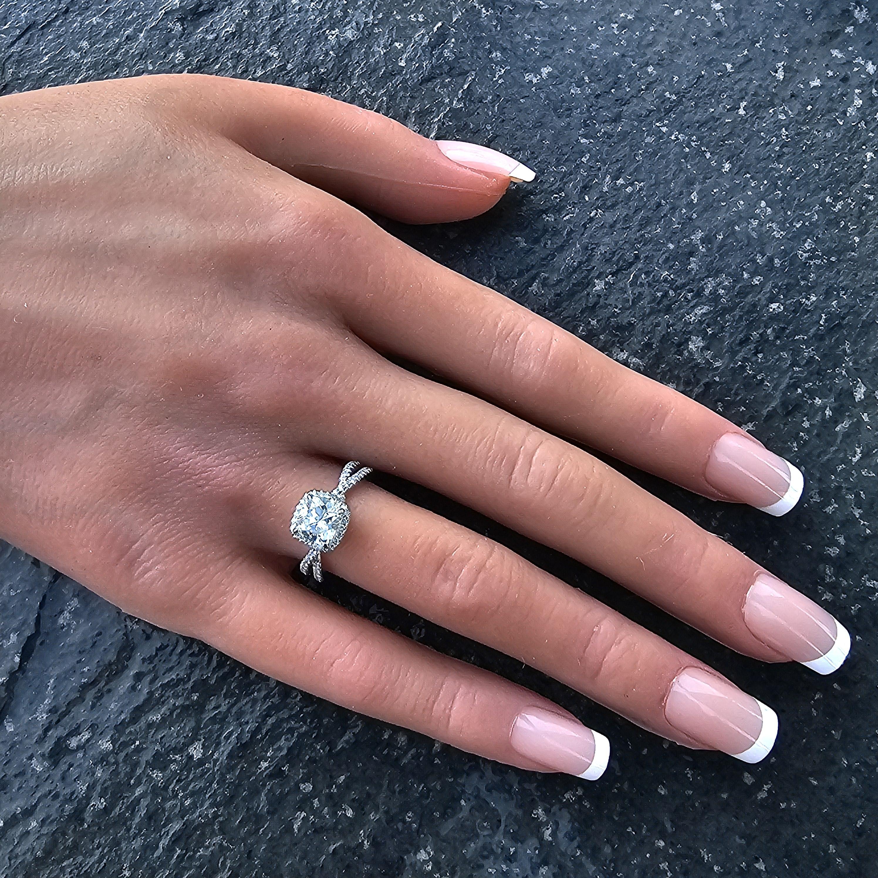 Este es un impresionante anillo de compromiso David Yurman Infinity con halo de pala completa, elaborado en platino, con un diamante talla cojín en el centro. El diamante, de 1,16 quilates, está rodeado por un halo de diamantes más pequeños, que