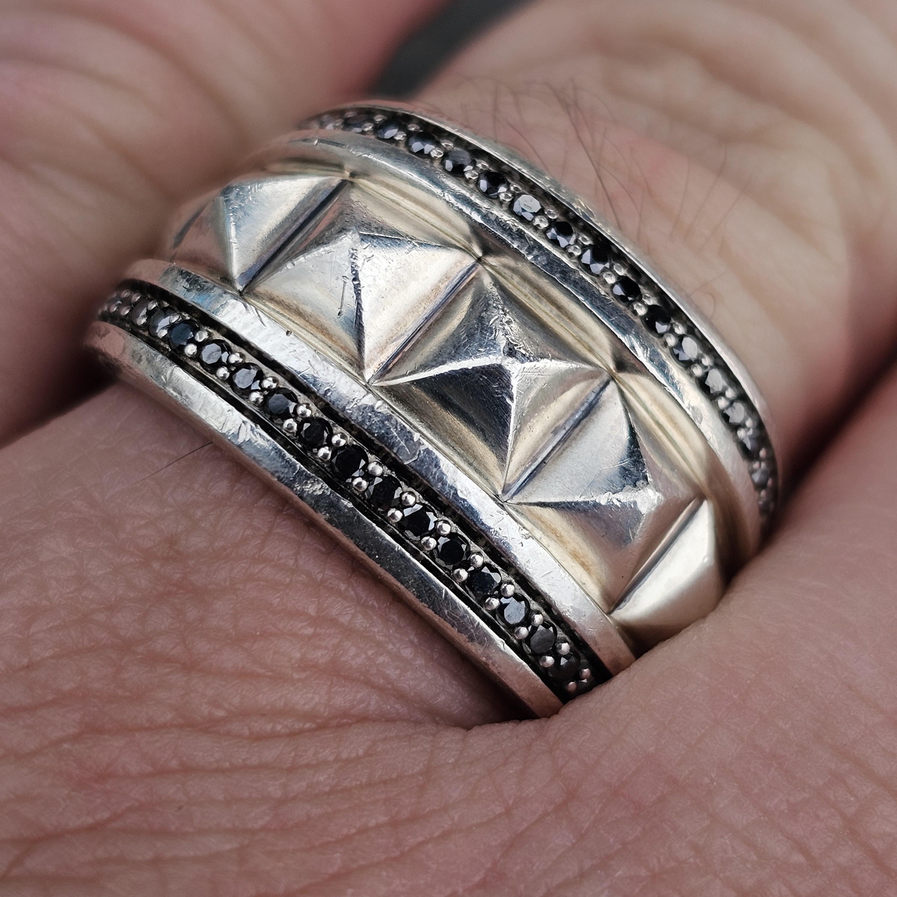 Hier haben wir einen David Yurman Pyramid Siegelring, Größe 11. Dieses Schmuckstück ist mit auffälligen schwarzen Diamanten besetzt, die das Band umgeben und das kühne geometrische Design des Mittelteils betonen. Der Ring weist ein strukturiertes