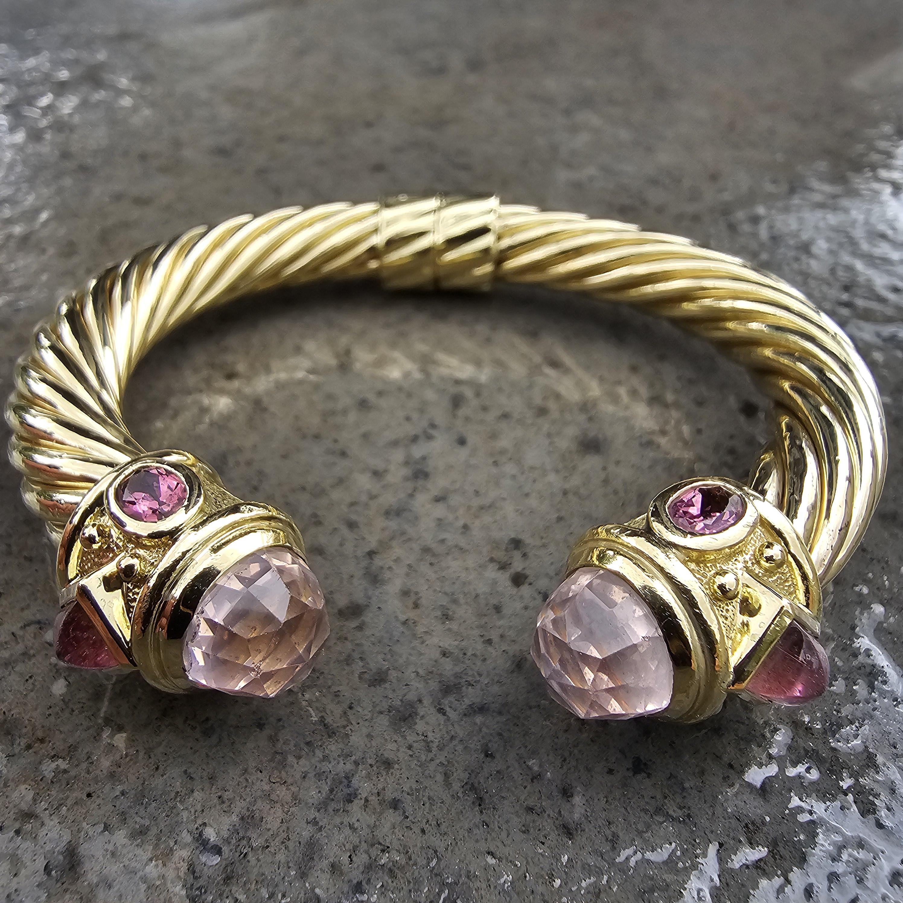 This David Yurman cuff bracelet is a captivating piece of fine jewelry. Crafted from 18k yellow gold, it features a twisted design that exudes sophistication. The bracelet is adorned with pink rose quartz stones, adding a subtle yet striking touch