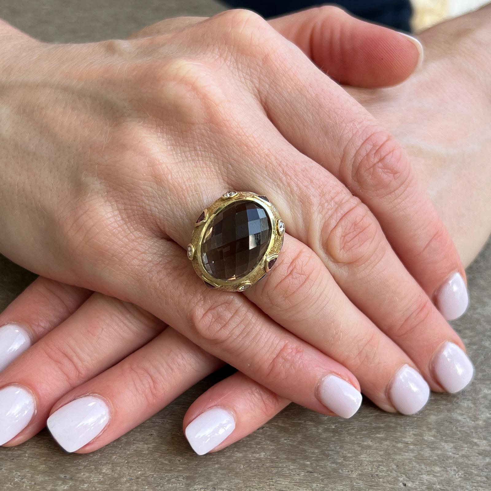 David Yurman Renaissance ring fashioned in sterling silver and 18 karat yellow gold. The cable ring features a faceted oval smokey topaz gemstone set in 18 karat yellow gold. The gold top also features bezel set diamond and garnet accents. The ring