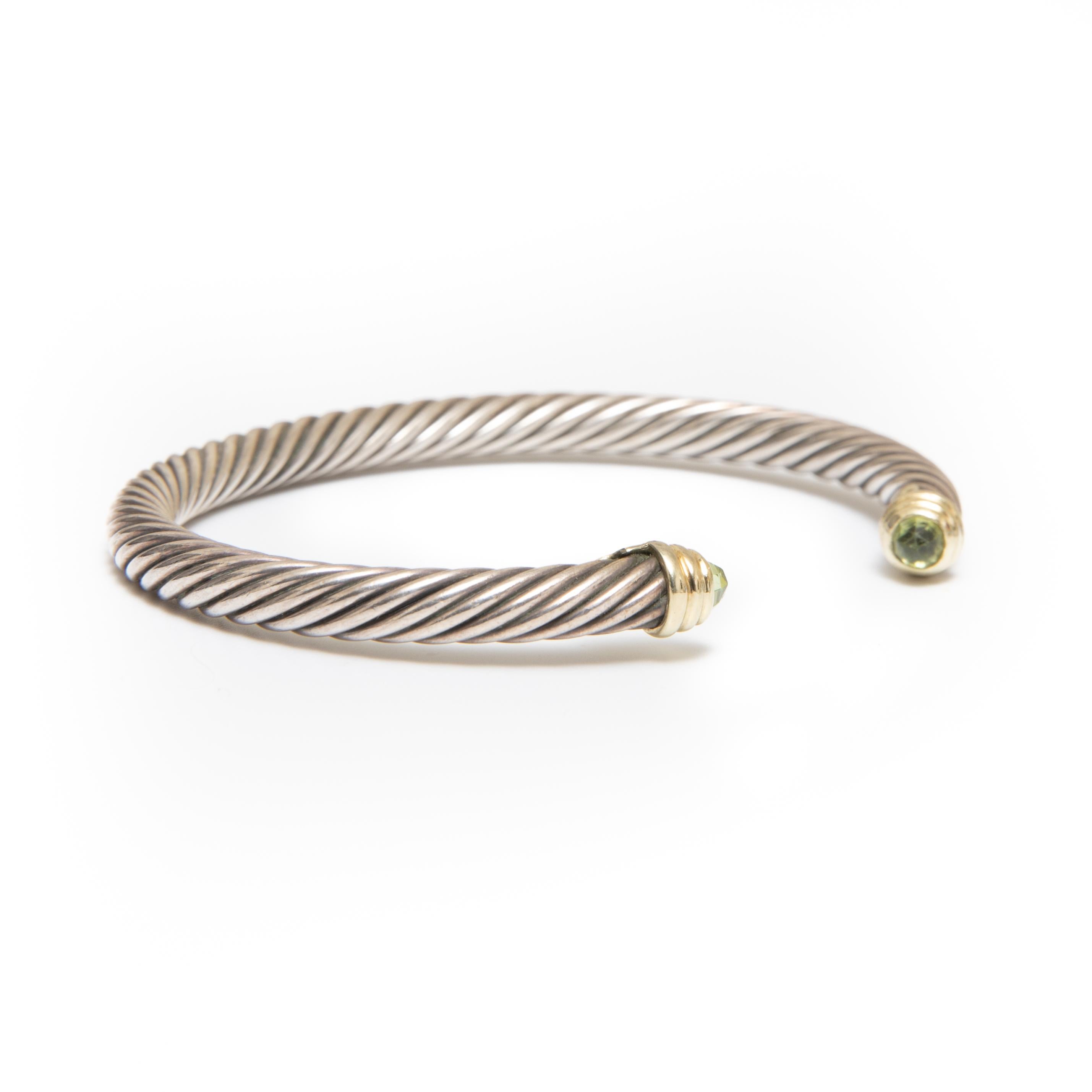 David Yurman Signed Two-Tone (Sterling Silver/14k Yellow Gold) Waverly Peridot  Cable Cuff Bracelet. The classic cable design element creates movement, texture, and depth, the ends contain a faceted with Peridot  and gold accents. 
David Yurman is a