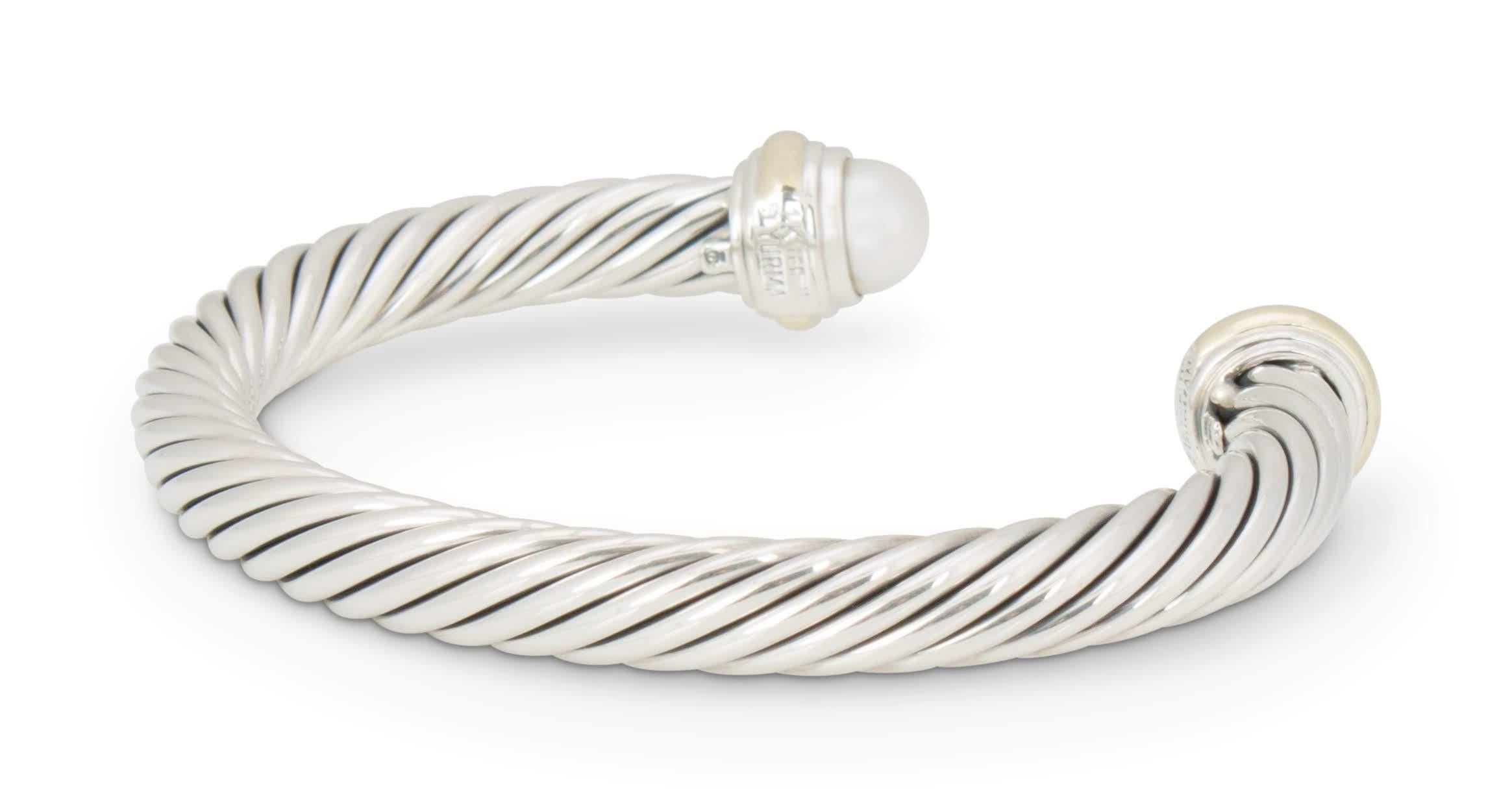 Authentic David Yurman Cable bracelet created in sterling silver with 14 karat gold accents and featuring 2 pearls measuring approximately 7mm each.  Bracelet measures 2 1/4 inches in diameter and can fit up to a size 6 1/2 wrist.  Signed 14K,