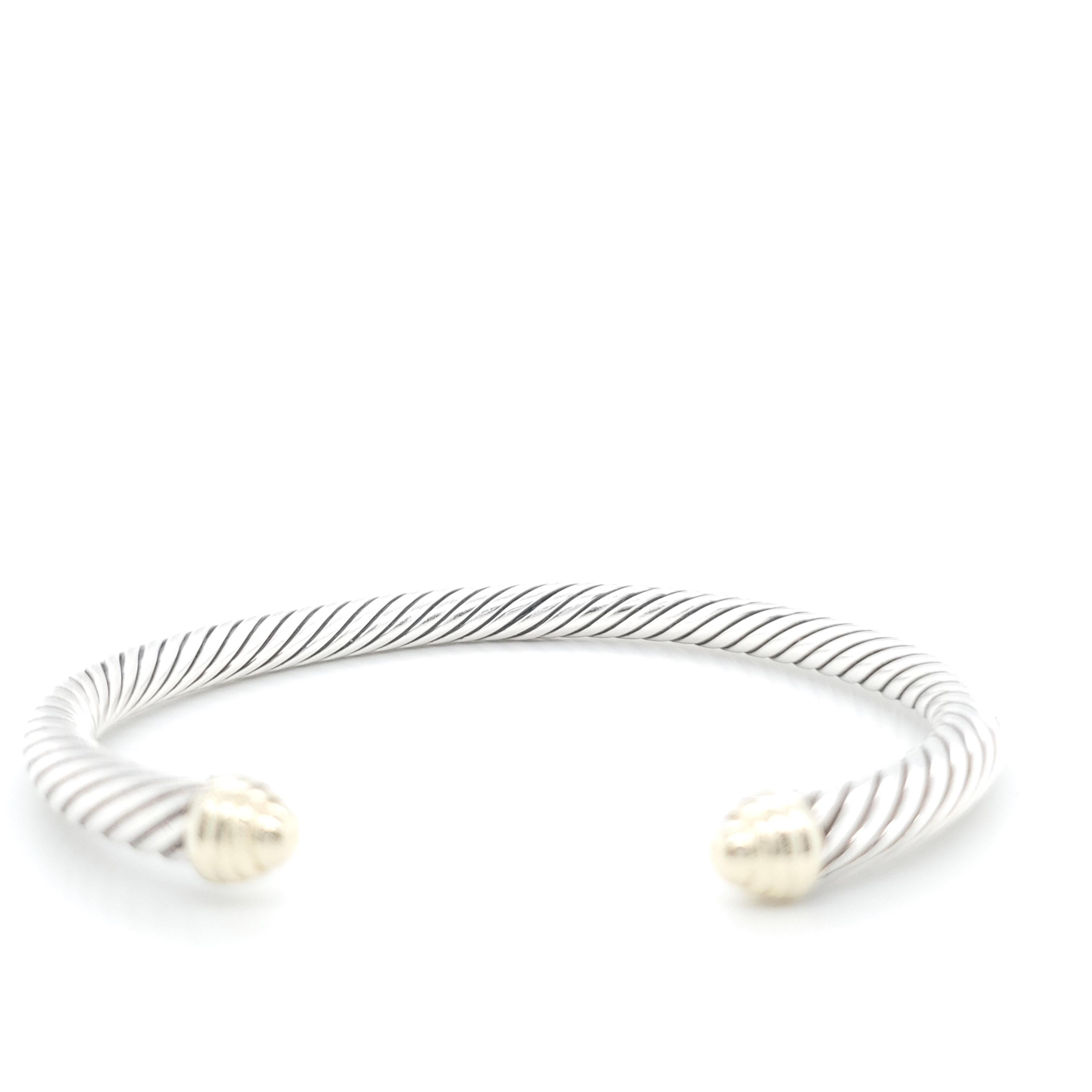 Authentic David Yurman sterling silver cable open cuff bangle with 14 karat yellow gold accent at each end. Cable is 5mm in width and the bangle measures 7 inches in diameter. Signed D.Y. 585 925. Condition issue: Bangle is bent out of round. Does