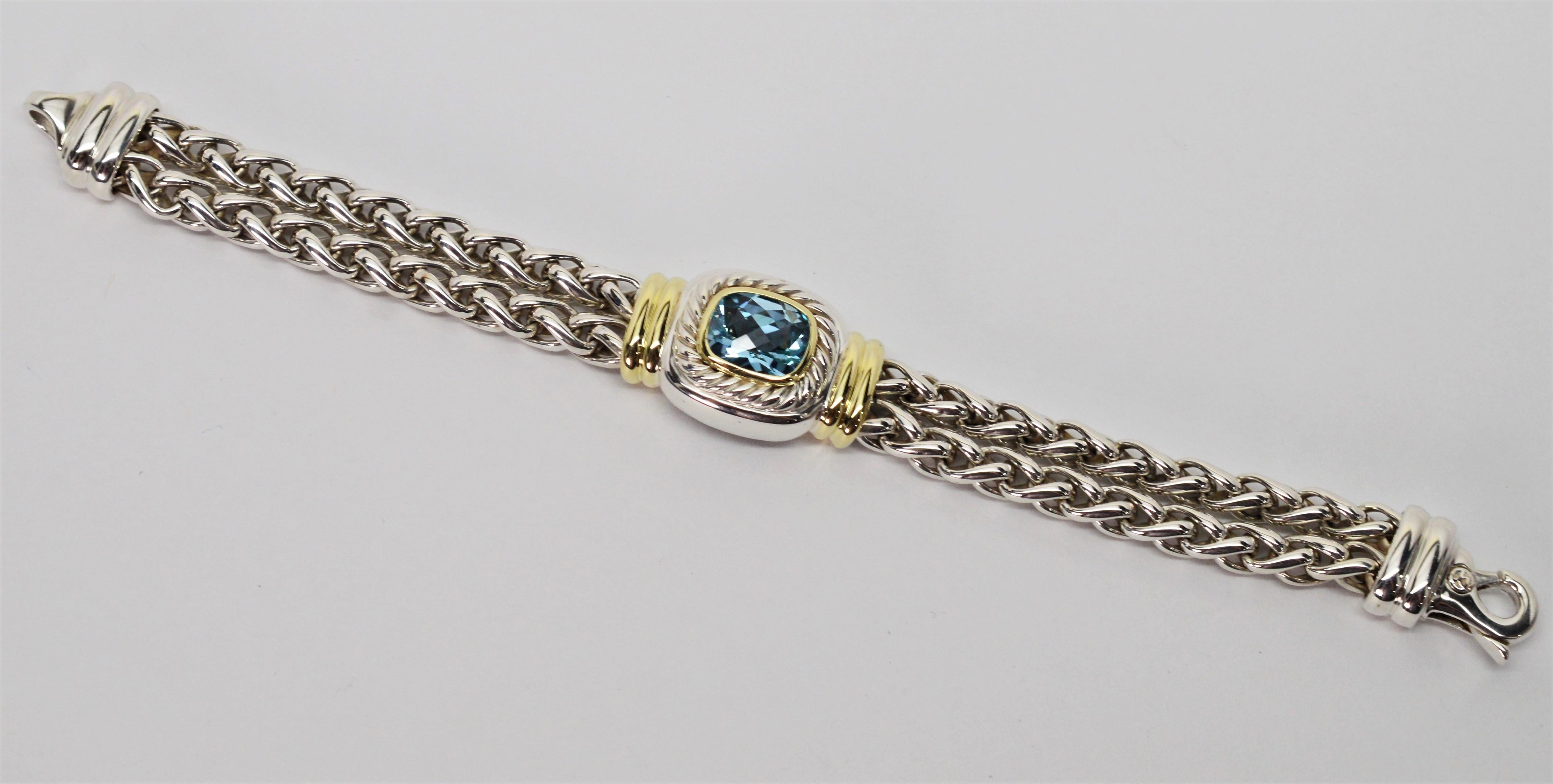 Desirable and timeless piece by designer David Yurman. The seven inch bracelet is crafted with a sterling silver double wheat chain and stunning DY charm with a large 9 x 11 mm cushion cut blue topaz bezel set in 14 K yellow gold accents. The piece