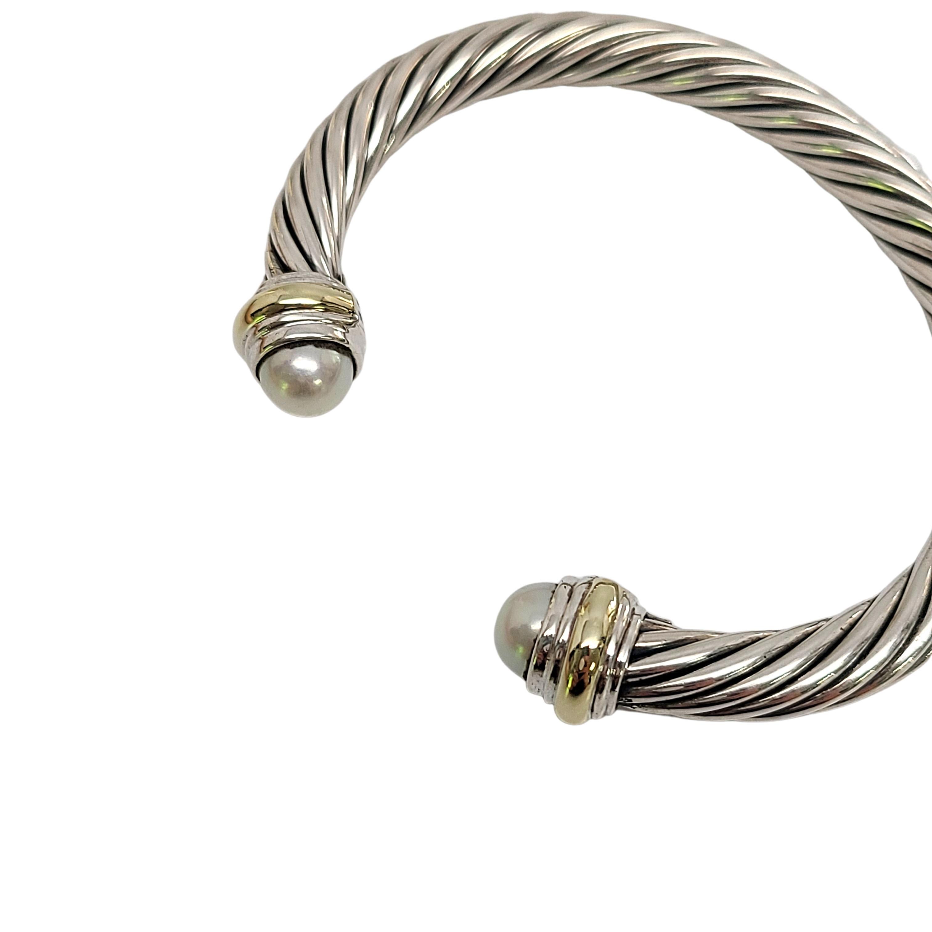 Sterling silver with 14K yellow gold accent and pearl cuff bracelet by designer David Yurman.

Signature sterling silver Cable Classics design accented with 14K yellow gold and a white cultured pearls at each end.

Measures 7mm thick, 6 1/4