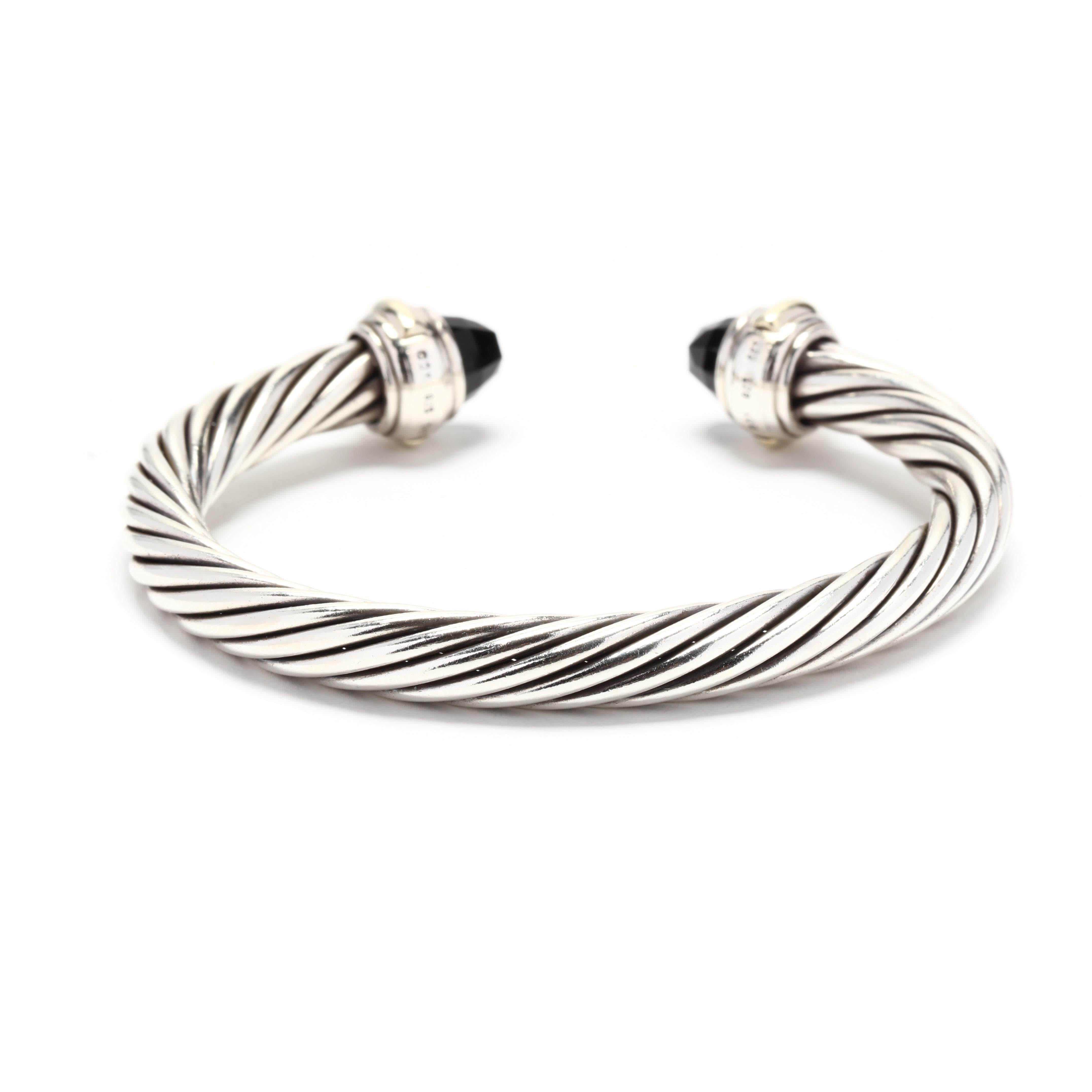A 14 karat yellow gold and sterling silver black onyx cuff bracelet by David Yurman. This bracelet features a silver cable cuff design with faceted black onyx end caps and yellow gold detailing.



Length: 6.25 in.; adjustable



Width: 7