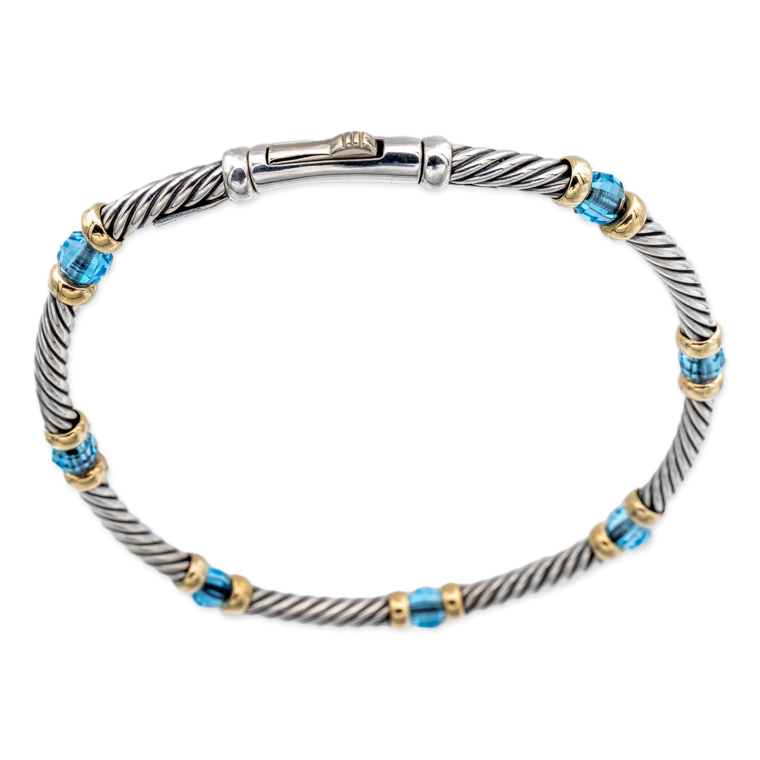 David Yurman wire bracelet finely crafted in sterling silver featuring 7 Briolette cut blue topaz beads set in between 14 karat yellow gold bars. Bracelet is flexible and has a hinged push-down clasp. Measures 3mm wide. Fits wrists up to 6.5 inches.