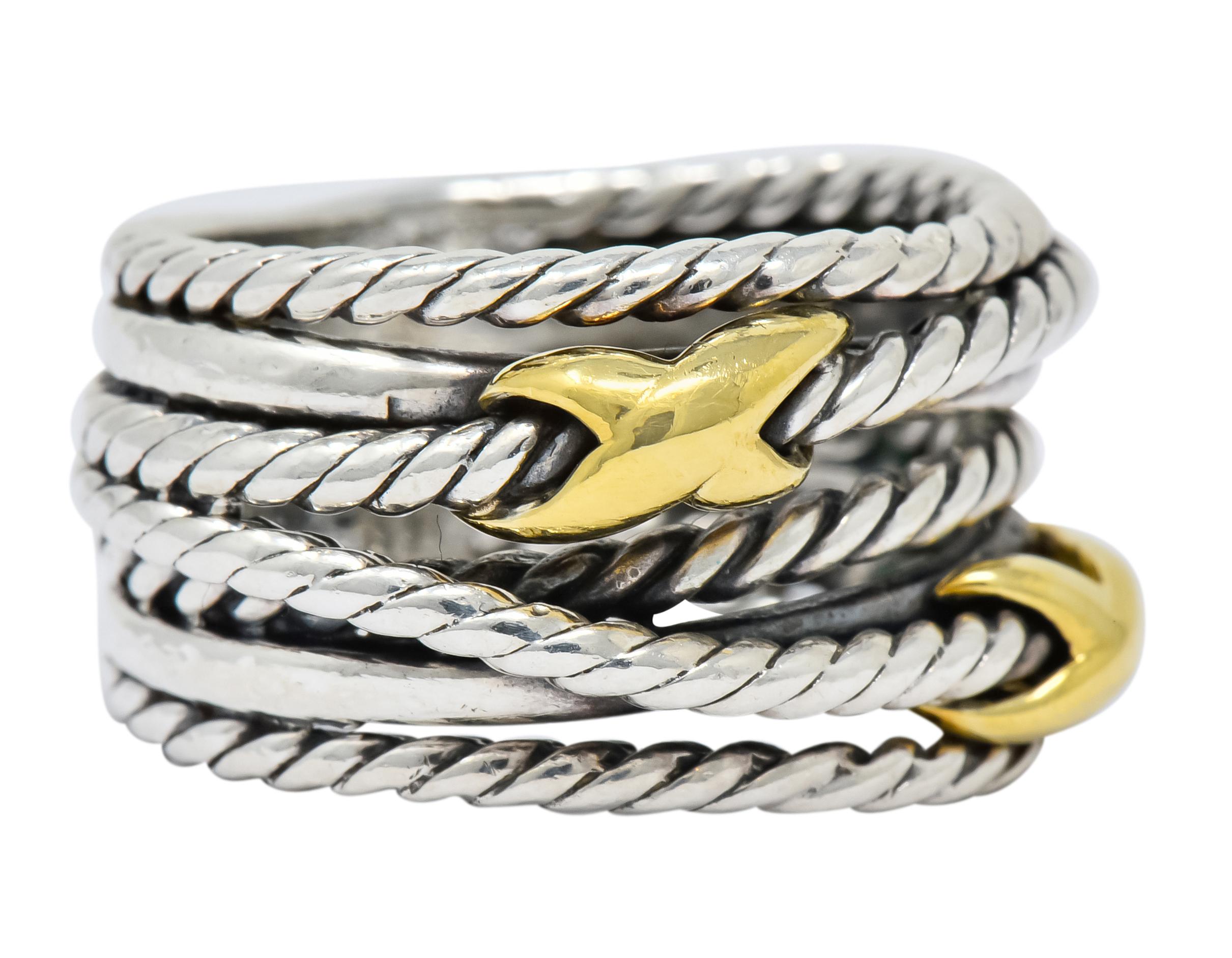 Comprised of seven intersecting sections with twisted cable motif

Accented by two polished gold “X” stations 

Signed DY David Yurman 

Stamped 925 and 750 for sterling silver 18 karat gold, respectively

Ring size 5.5

Top measures: 11.5 mm and