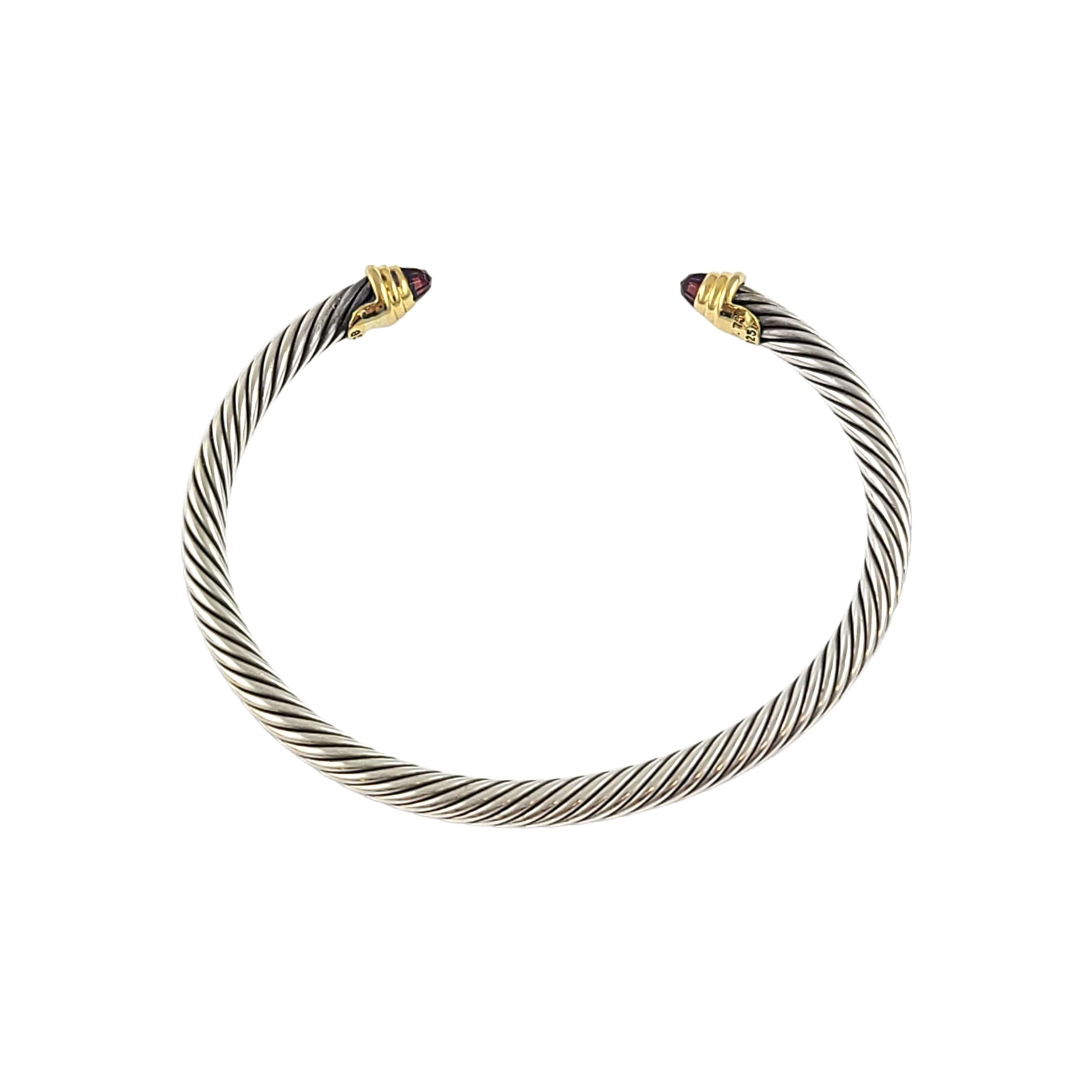 Sterling silver 18K yellow gold and garnet classic cable cuff bracelet by David Yurman.

Features Yurman's classic cable design in sterling silver with 18K yellow gold accent and a faceted garnet at each end.

Measures approx 6