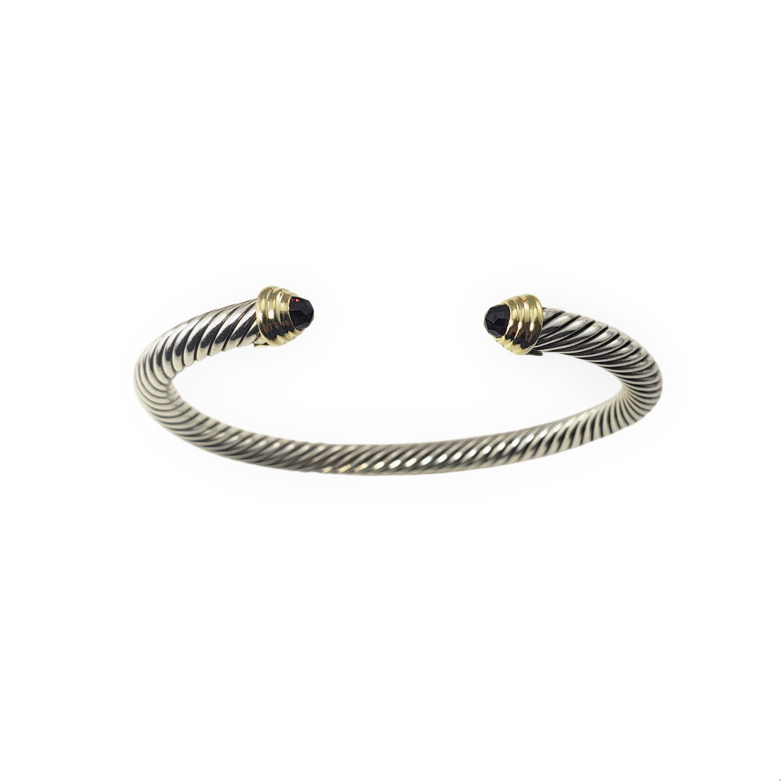 David Yurman Sterling Silver and 14 Karat Yellow Gold Garnet Cuff Bracelet-

This lovely cable bracelet by David Yurman is accented with two faceted garnets (3 mm) set in beautifully detailed sterling silver and 14K yellow gold.  Width:  5