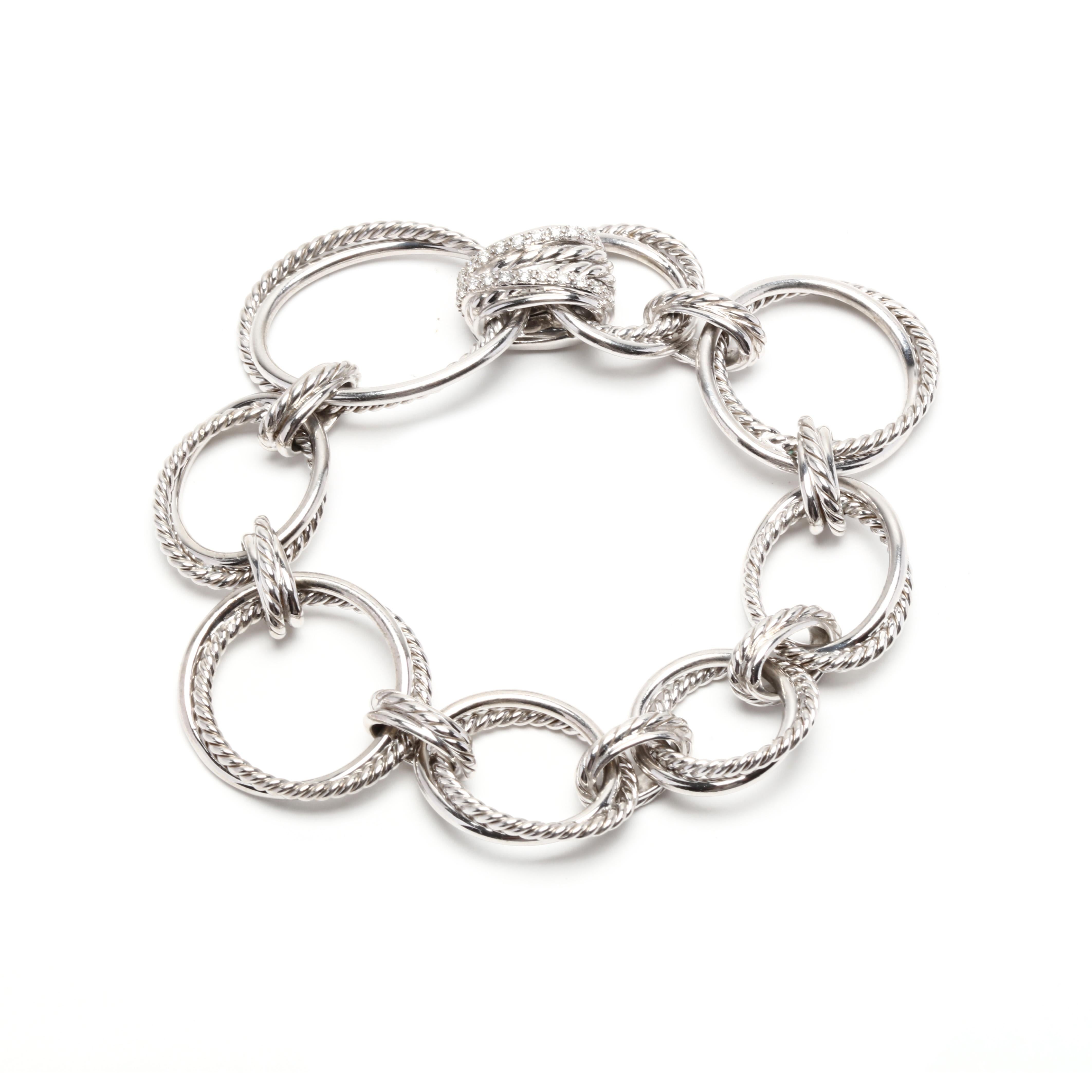 A David Yurman sterling silver and diamond infinity link bracelet. This bracelet features various size flat oval links with on polished and one cable motif row twisted together and with a diamond set clasp.

Stones:

- diamonds, 24 stones

- full