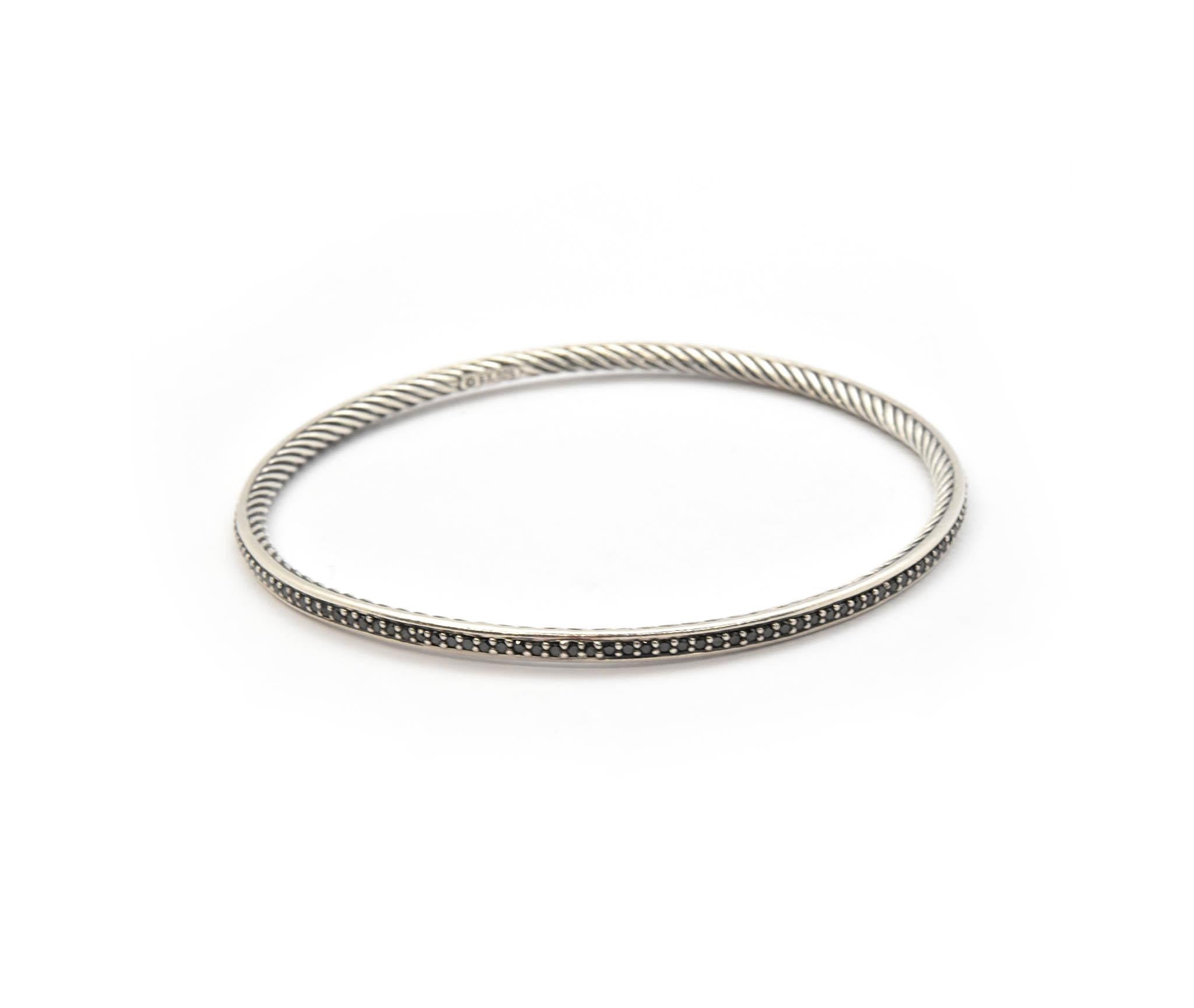 This David Yurman cable bangle is fashioned from sterling silver and set with black diamonds on the outside of the bangle! The black diamonds are round and each is held into place by sterling silver prongs. Classic David Yurman cable designs are on