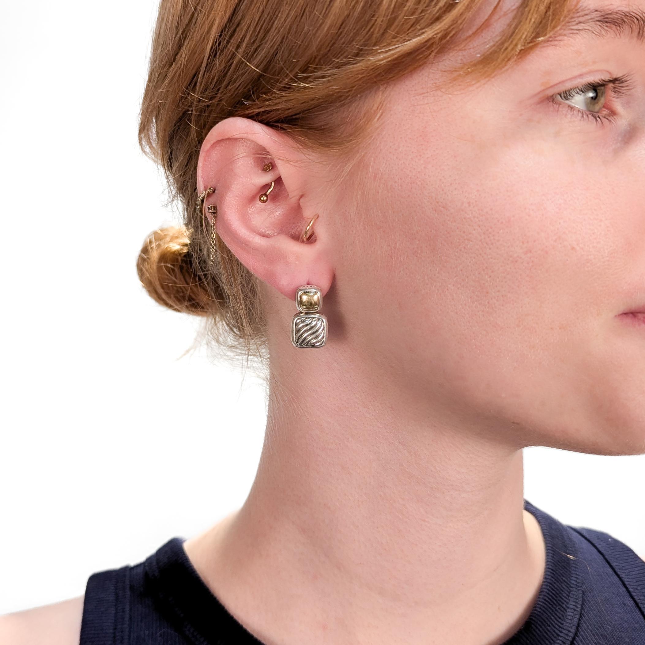 A fine pair of signed silver and gold earrings.

By David Yurman.

In sterling silver with 18 karat yellow gold accents.

With cable decoration around the edges and to the front of the drop.

Marked to the reverse of each.

Each with a pushback