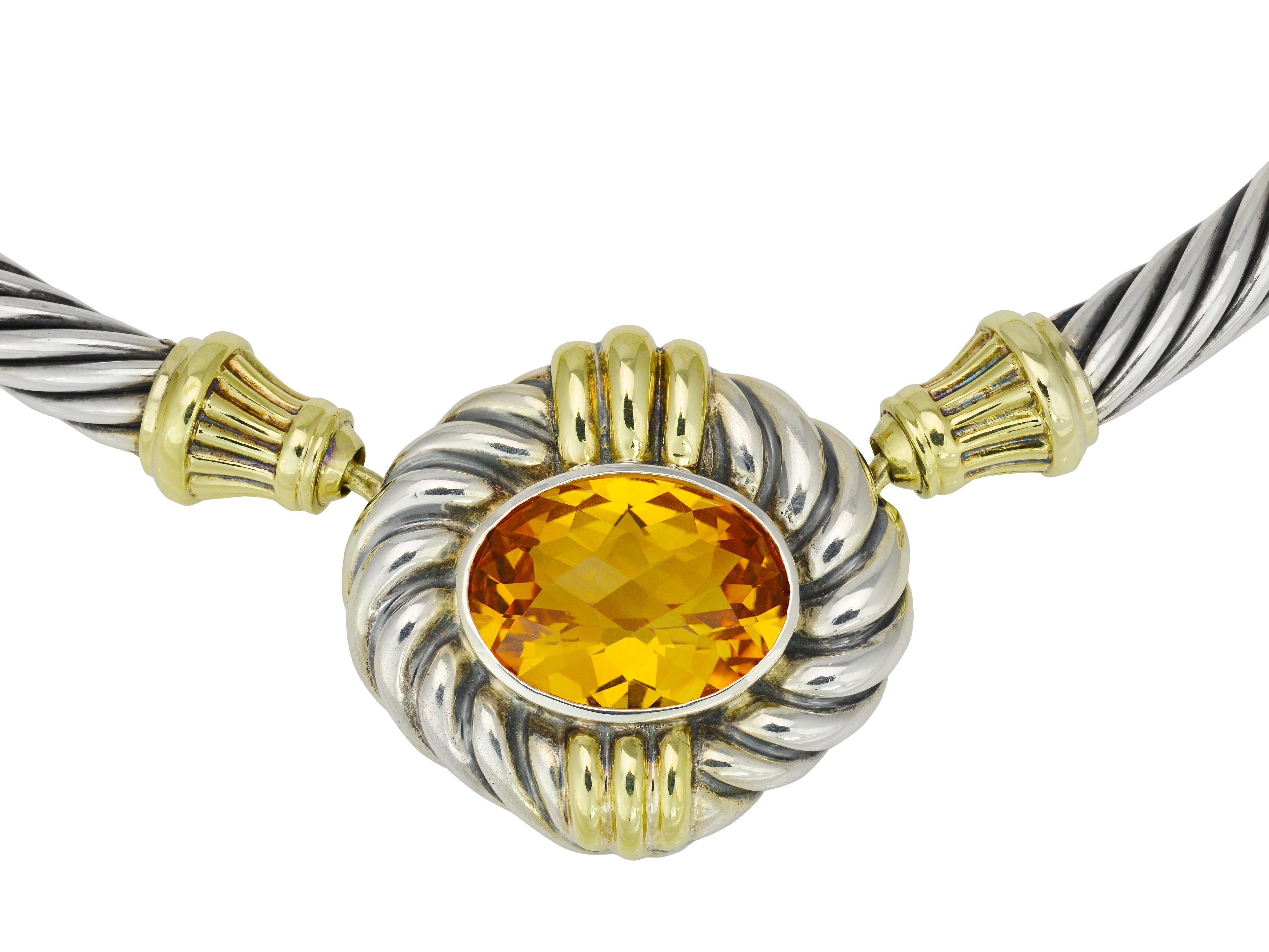 This sterling silver and 14 karat yellow gold cable necklace from David Yurman lays directly on the collar. It features a large faceted oval citrine quartz center stone in a yellow gold bezel setting. The cable necklace is articulated in 5 spots for