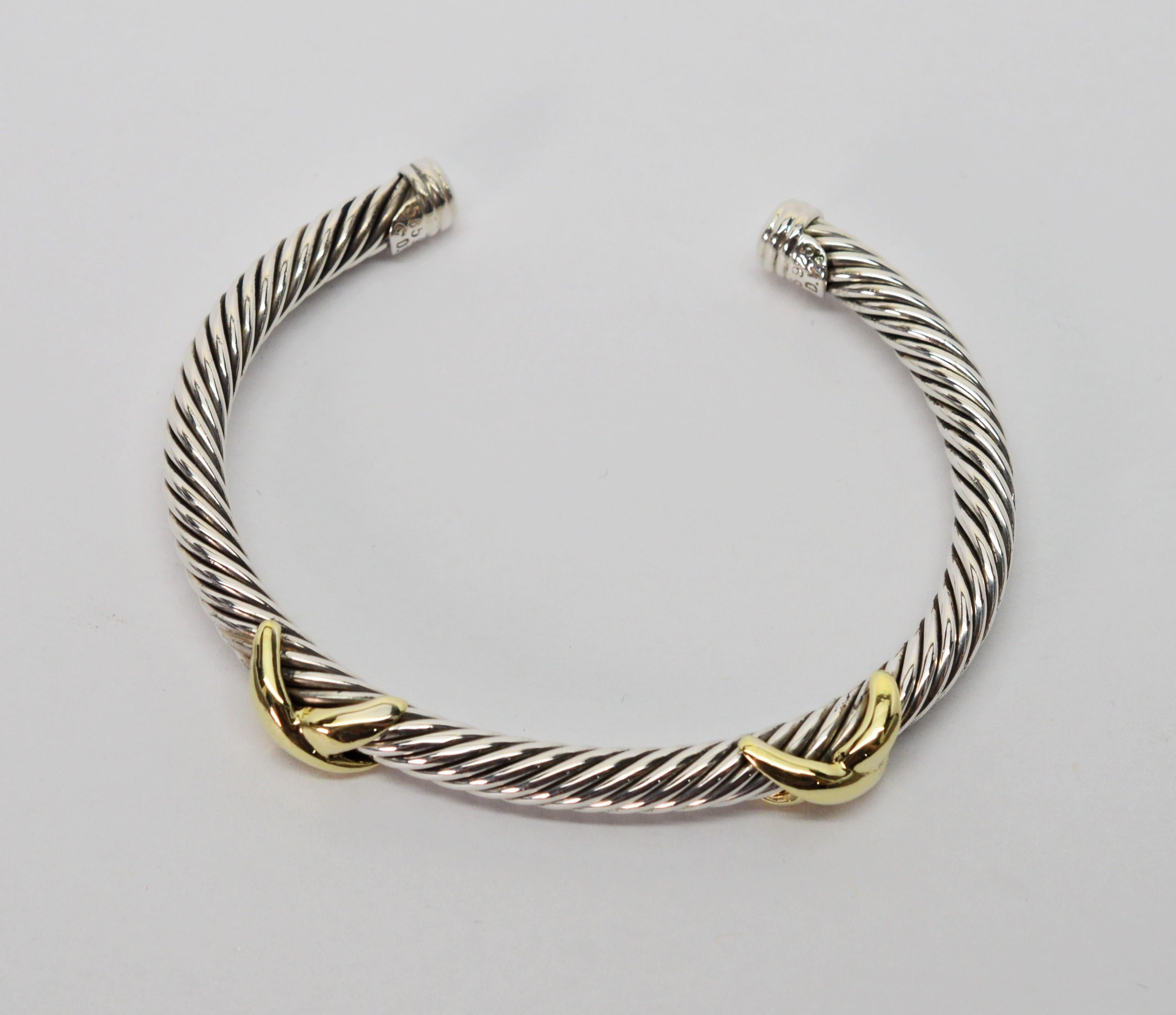 This mixed-metal bracelet is a classic piece from famed designer David Yurman. The open-style criss-cross cuff features Yurman's rope twist design in solid .925 sterling silver studded with two fourteen carat 14k yellow gold Xs. The cuff's terminals