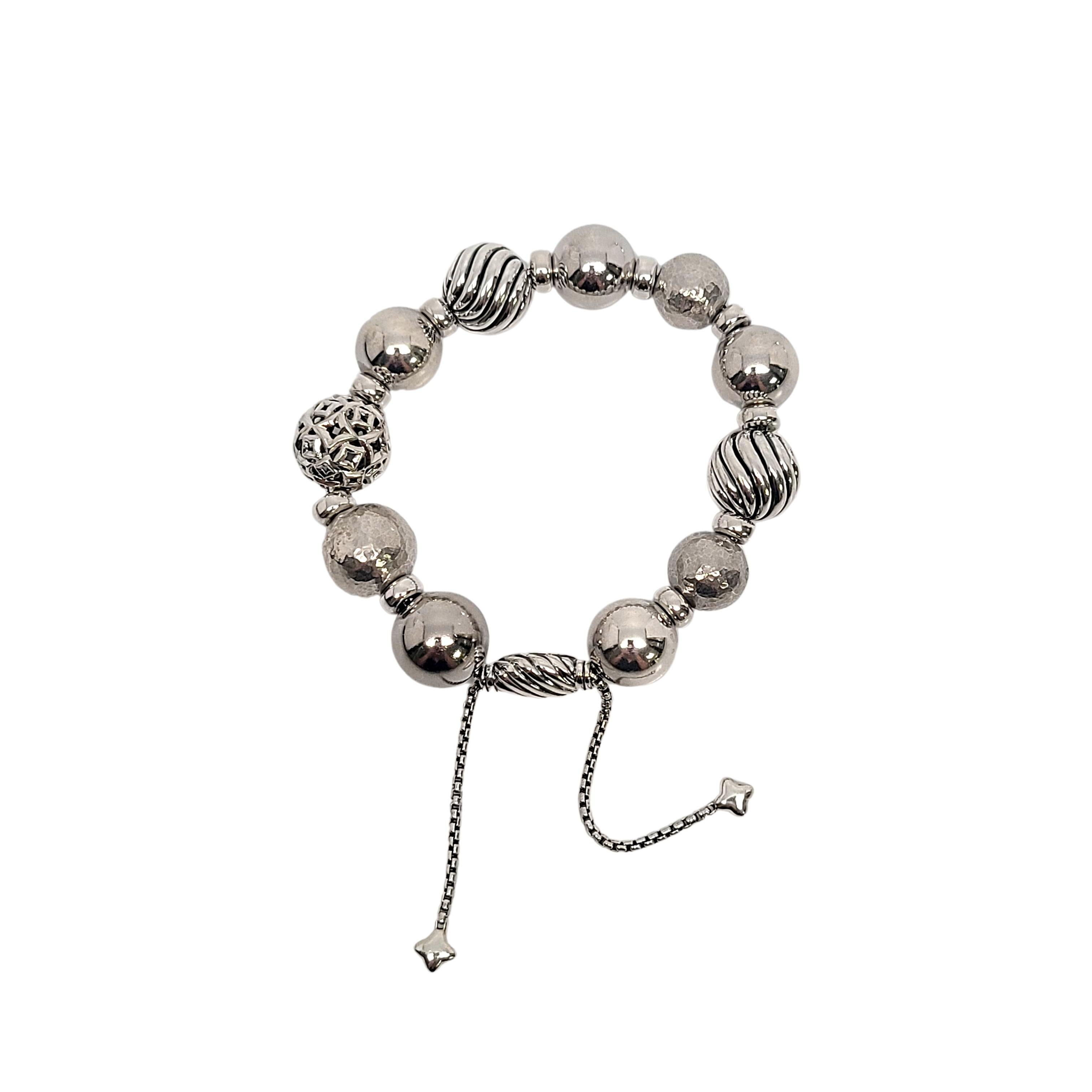 Sterling silver Elements bead bracelet by David Yurman

This beautiful sterling silver bracelet by David Yurman features large round silver beads, different textures of the beads include polished, hammered, ribbed and open work design. Bolo closure