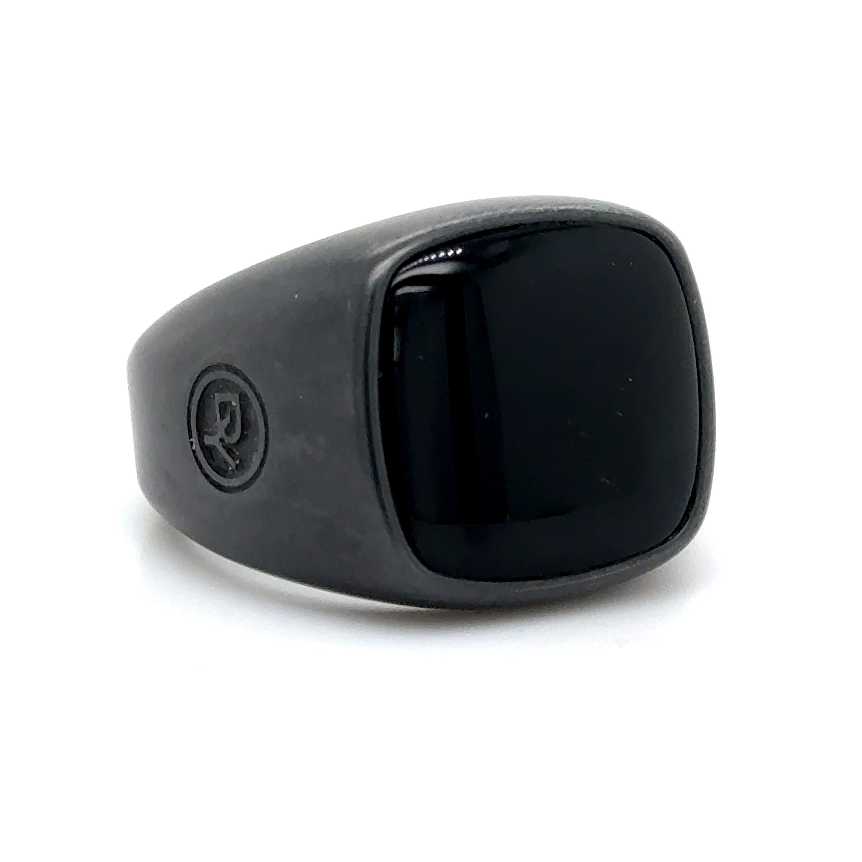   David Yurman stands out with this phenomenal mens signet ring. The ring is crafted in black titanium and shows a sleek finish. The ring highlights one 18 mm onyx gemstone, handpicked for its symbolism and coloration. The ring shows a 19 mm width