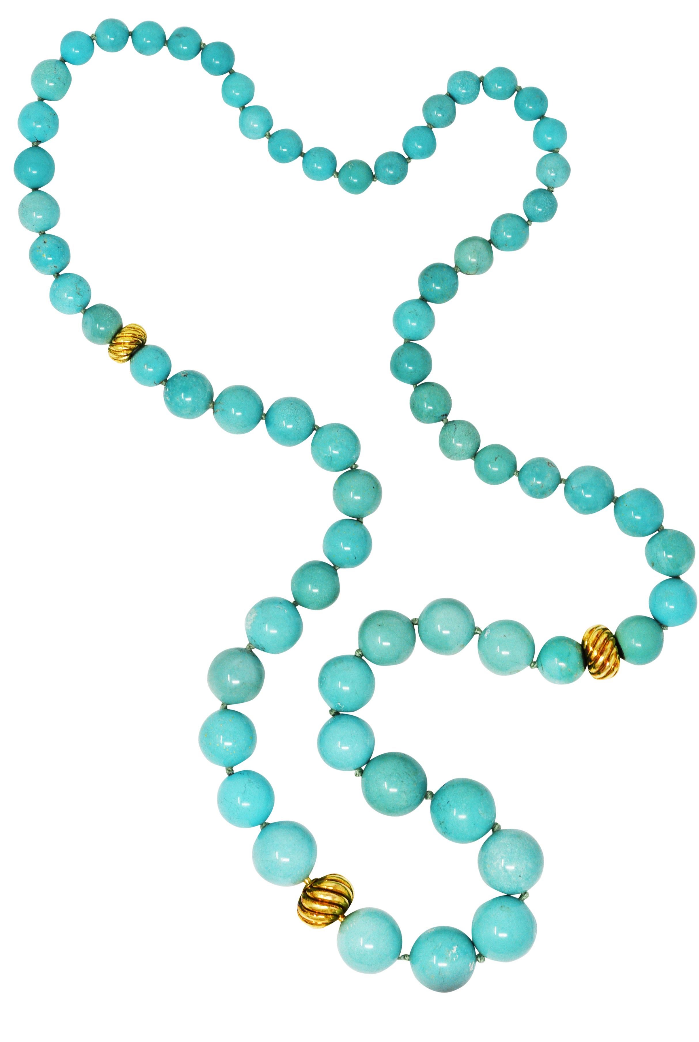 Necklace is comprised of round turquoise beads graduating in size from 10.0 mm to 18.0 mm. Opaque light greenish blue in color with white mottling and subtle gray, black, and brown matrix. Accented by three gold grooved twisted cable motif beads -