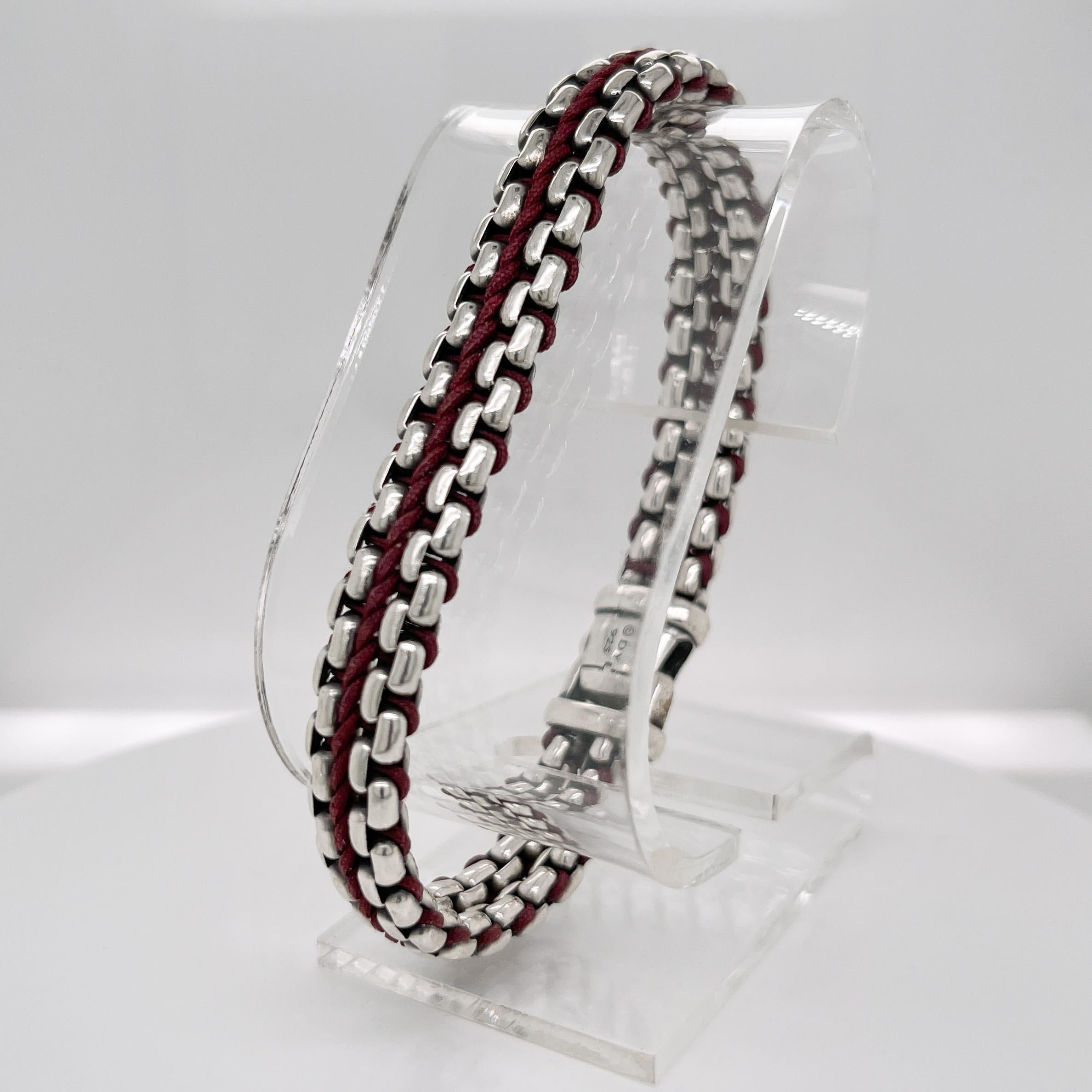 A fine David Yurman braclet.

In sterling silver. 

With a burgundy nylon cord woven between the silver links. 

Marked to the clasp copyright DY & 925

Simply a handsome bracelet!

Date:
21st Century

Overall Condition:
It is in overall good,