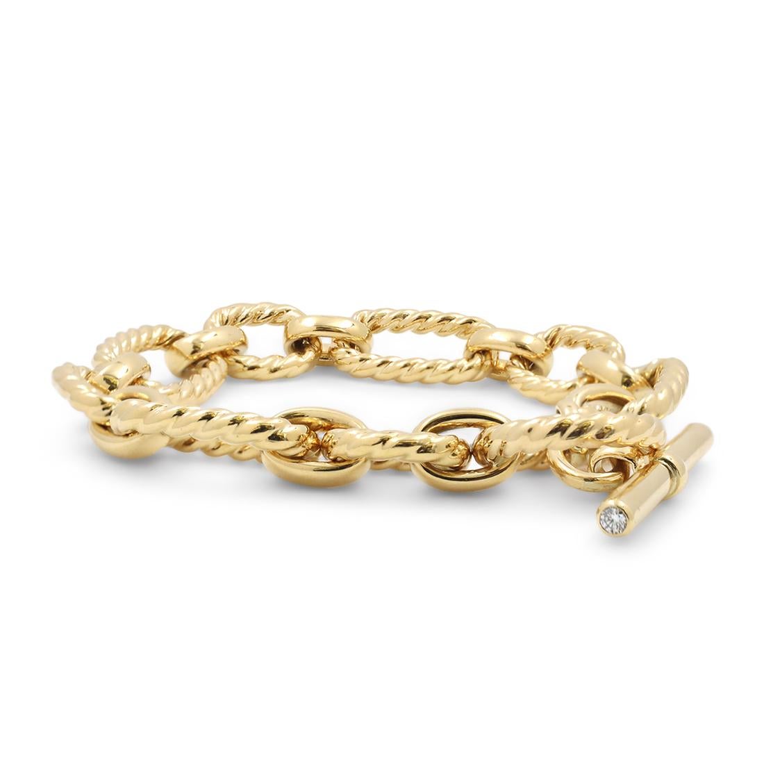Authentic David Yurman bracelet crafted in 18 karat yellow gold comprised of high-polished links inspired by David Yurman's classic cable design and featuring two round brilliant cut diamonds in the toggle. The bracelet measures 7 1/2 inches in