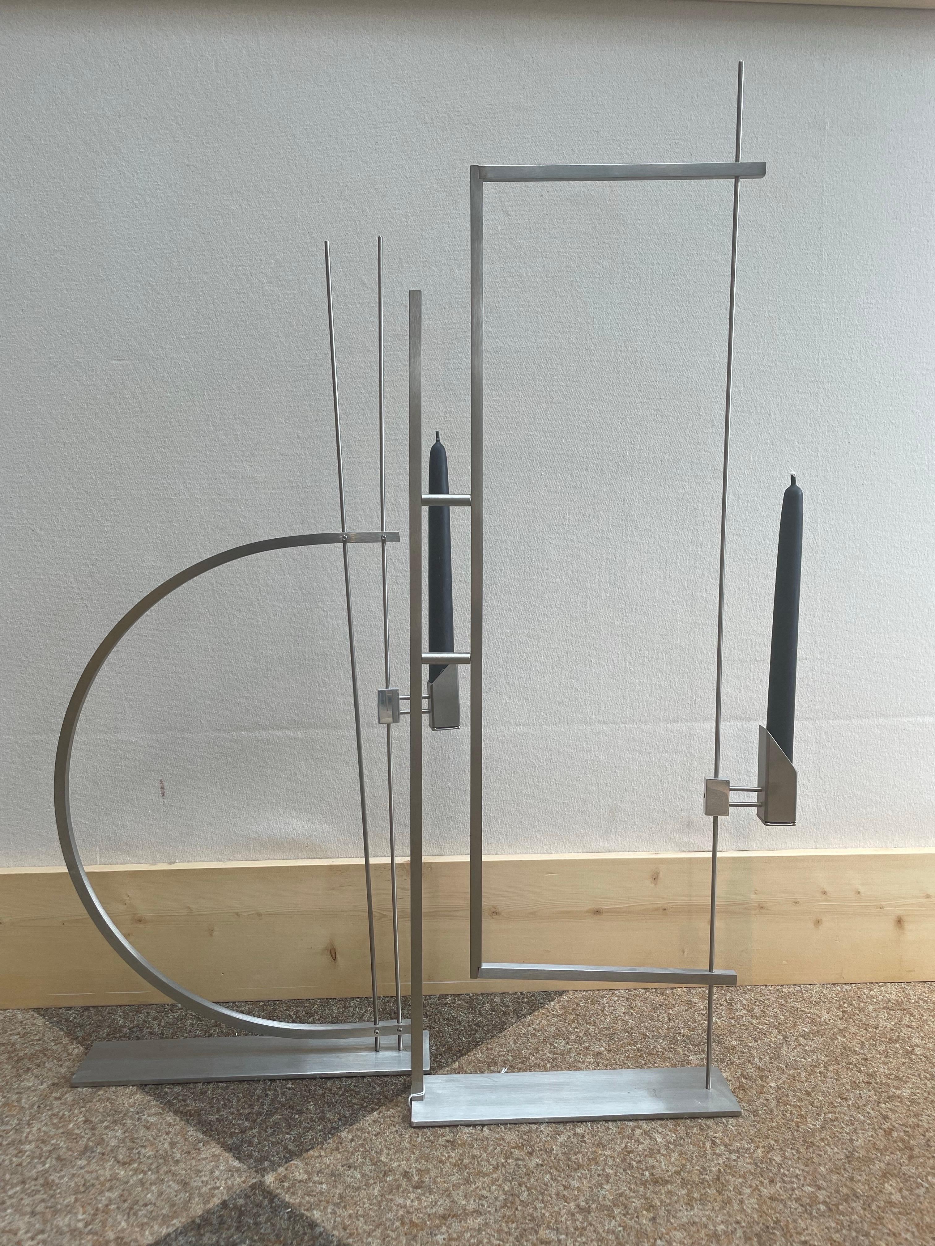 Rara coppia di candelabri scultorei disegnati da David Zelman per Prologue 2000, Inc., NYC, circa anni '80. Questi pezzi dinamici sono realizzati in acciaio inossidabile spazzolato e riflettono il caratteristico linguaggio architettonico e