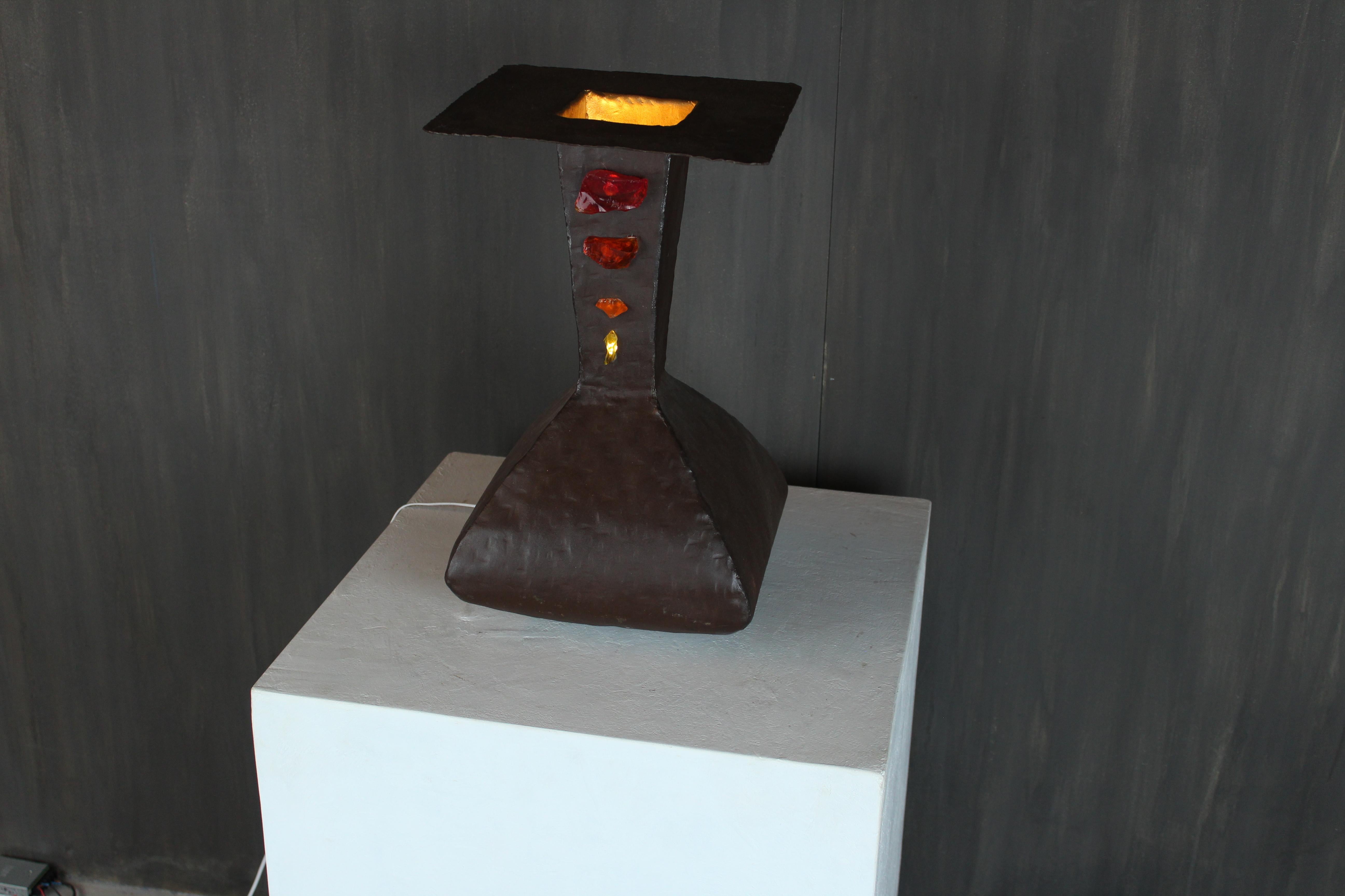 Una lámpara de mesa única hecha a mano por el artista italiano Davide Moretto, forjada en acero corten y engastada con fragmentos de cristal de Murano tallados a mano. Esta escultura luminosa revela el diálogo poético de Moretto entre la materia y