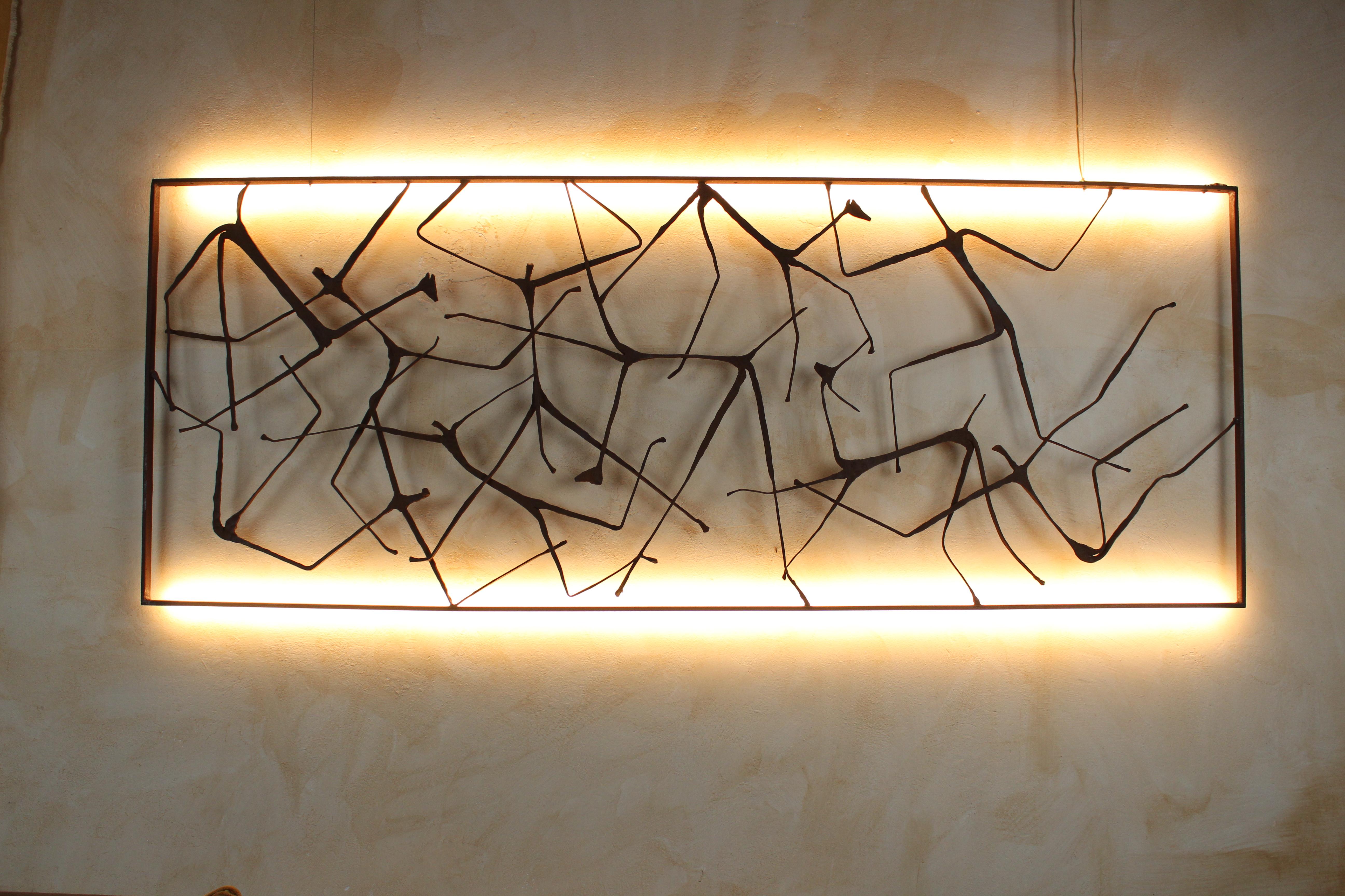 “Uomini e Animali” is a unique wall sculpture by Italian artist Davide Moretto, entirely handcrafted in forged Corten steel and illuminated by a concealed warm white LED system (CRI 98+). Each segment of the composition is hammered, stretched and