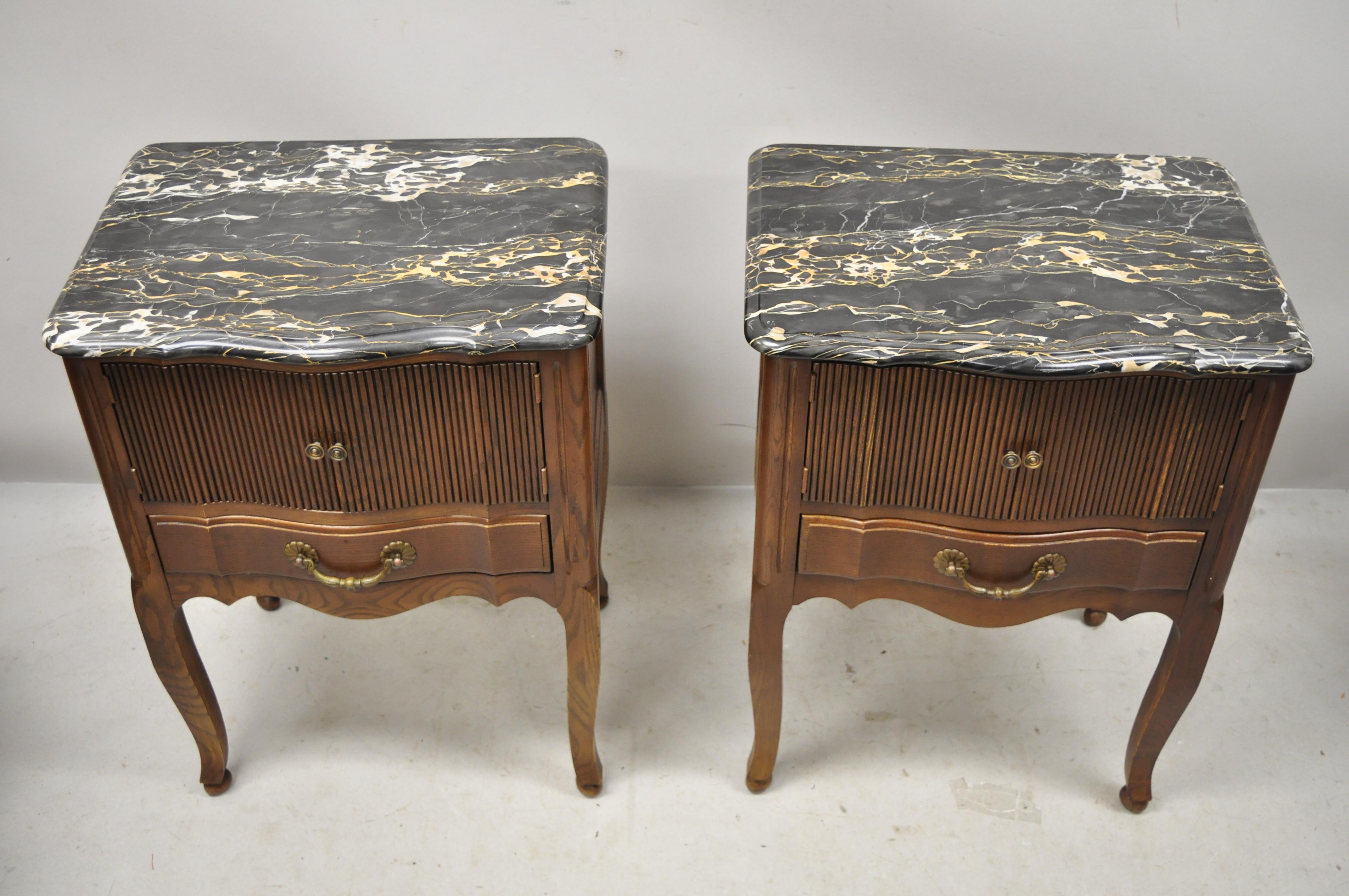 Davis Cabinet Company French country provincial oak marble-top nightstand bedside tables, a pair. Item features black marble tops, solid wood construction, beautiful wood grain, finished back, 2 swing doors, 2 drawers, cabriole legs, solid brass