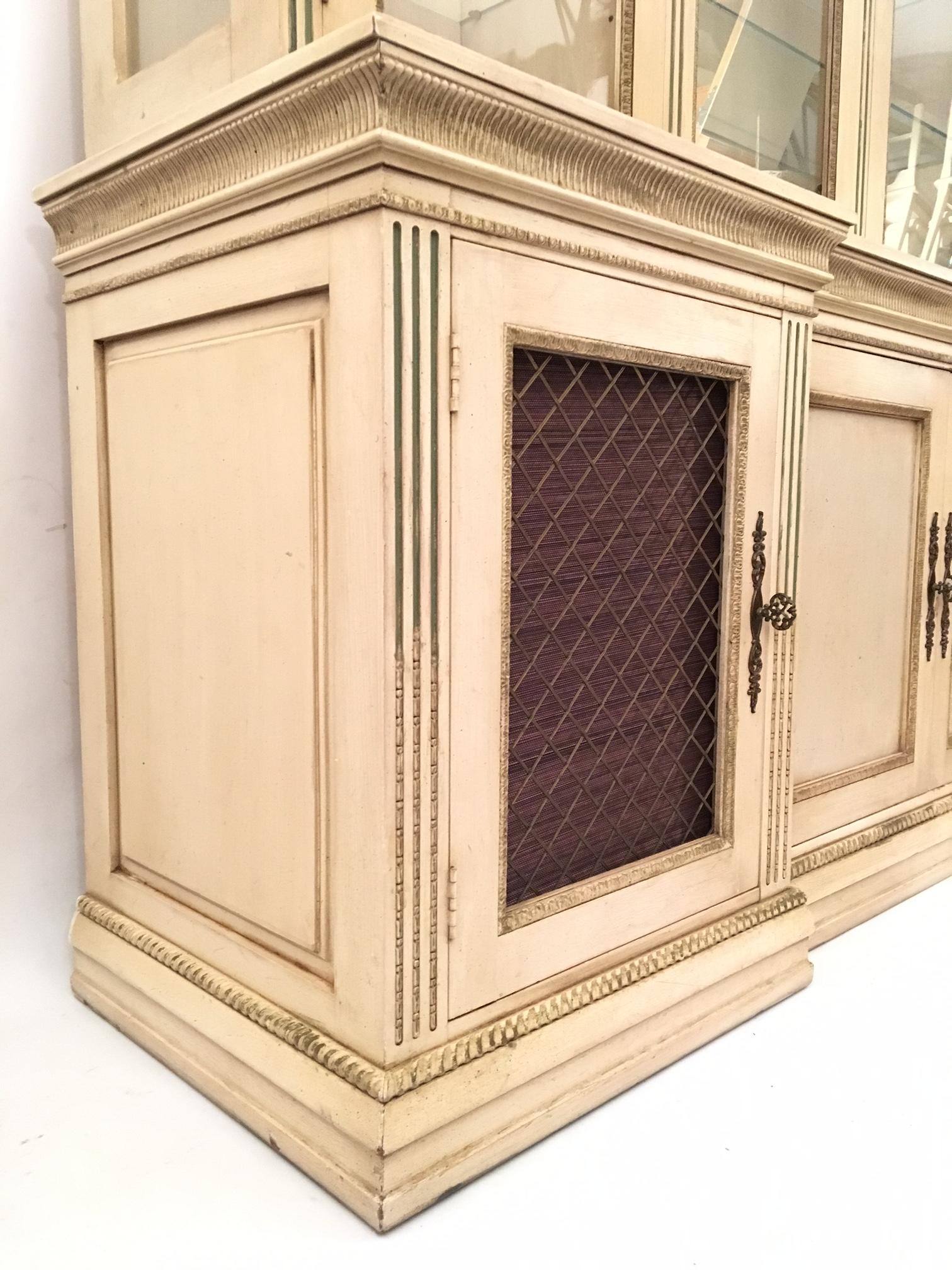 Monumental solid wood reverse breakfront hutch by Davis Cabinet Company features ornate pediment top, raised moldings and adjustable glass shelves. Original floral hardware. Gallery lights in top hutch illuminate display items sitting on adjustable