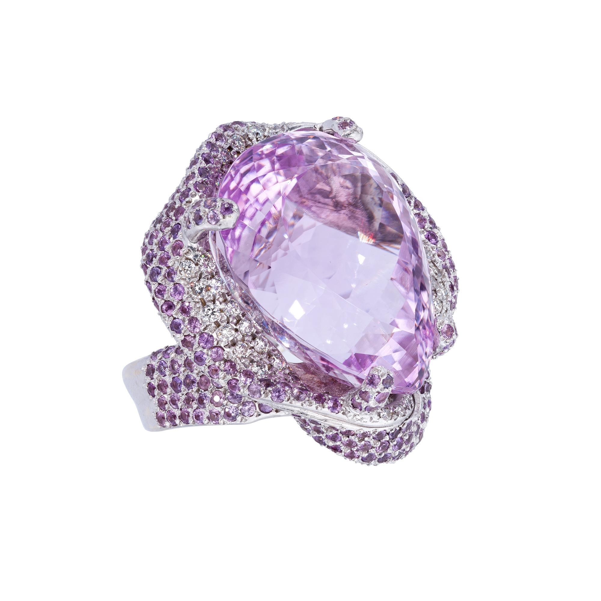 A Ring from d'Avossa Masterpiece Collection in white 18 kt gold with an outstanding Central Pear Shape Kunzite 72,62 ct (26mmx20mm) enhanced by a pavé of Pink Sapphires and White Diamonds.
Width: 29mm  Thickness: 33mm


Ref. Number AKU677

