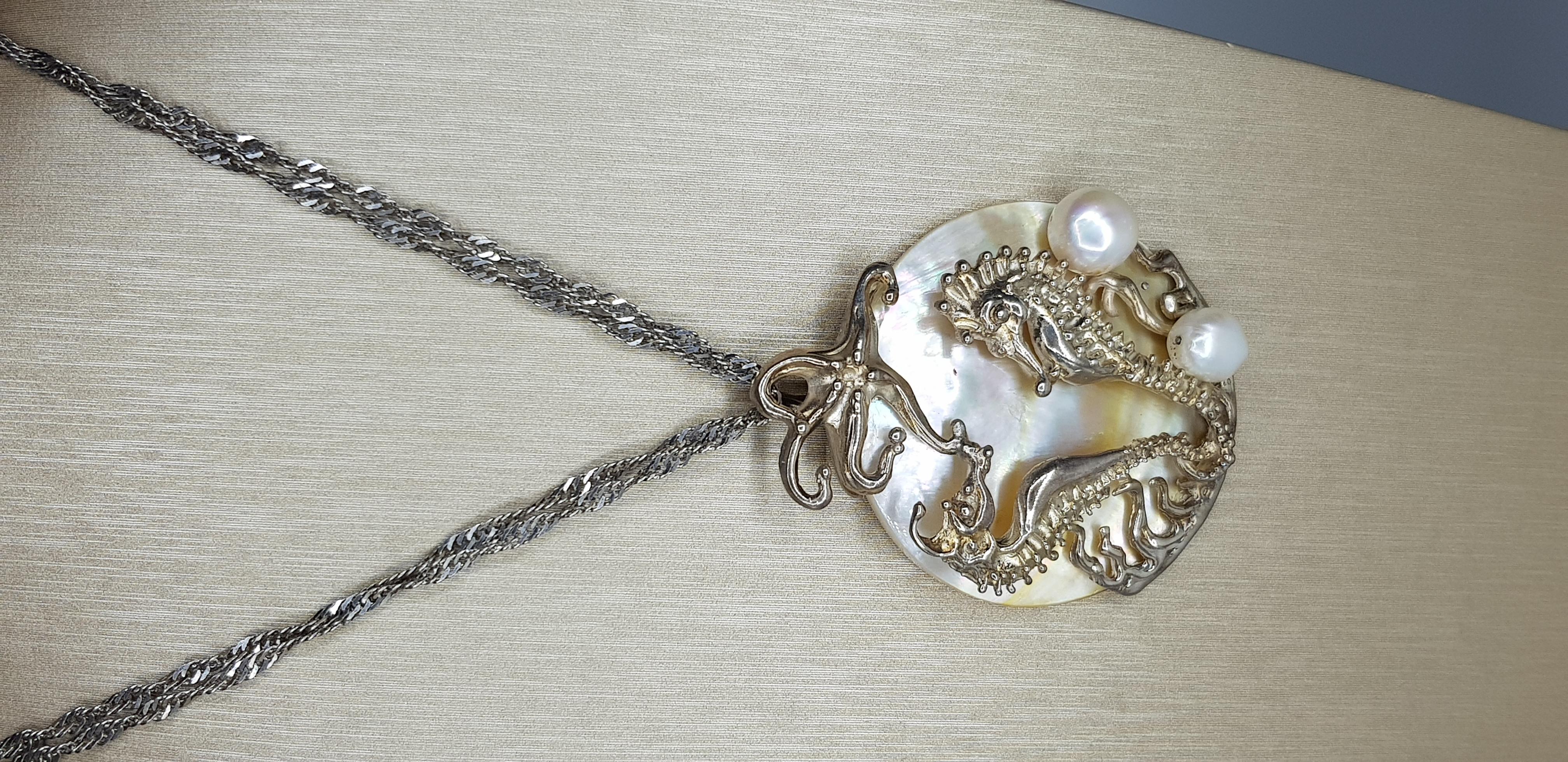 A one of a kind Sea Horse pendant necklace in sterling silver, attached to a mother of pearl disc with two fresh water pearls