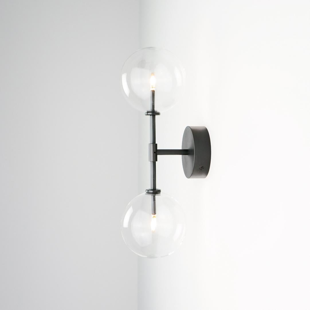 Dawn Dual brass wall sconce by Schwung
Dimensions: W 19 x D 15 x H 47.5 cm
Materials: Black gunmetal, hand blown glass globes

Finishes available: Black gunmetal, polished nickel, brass


Schwung is a German word, and loosely defined, means