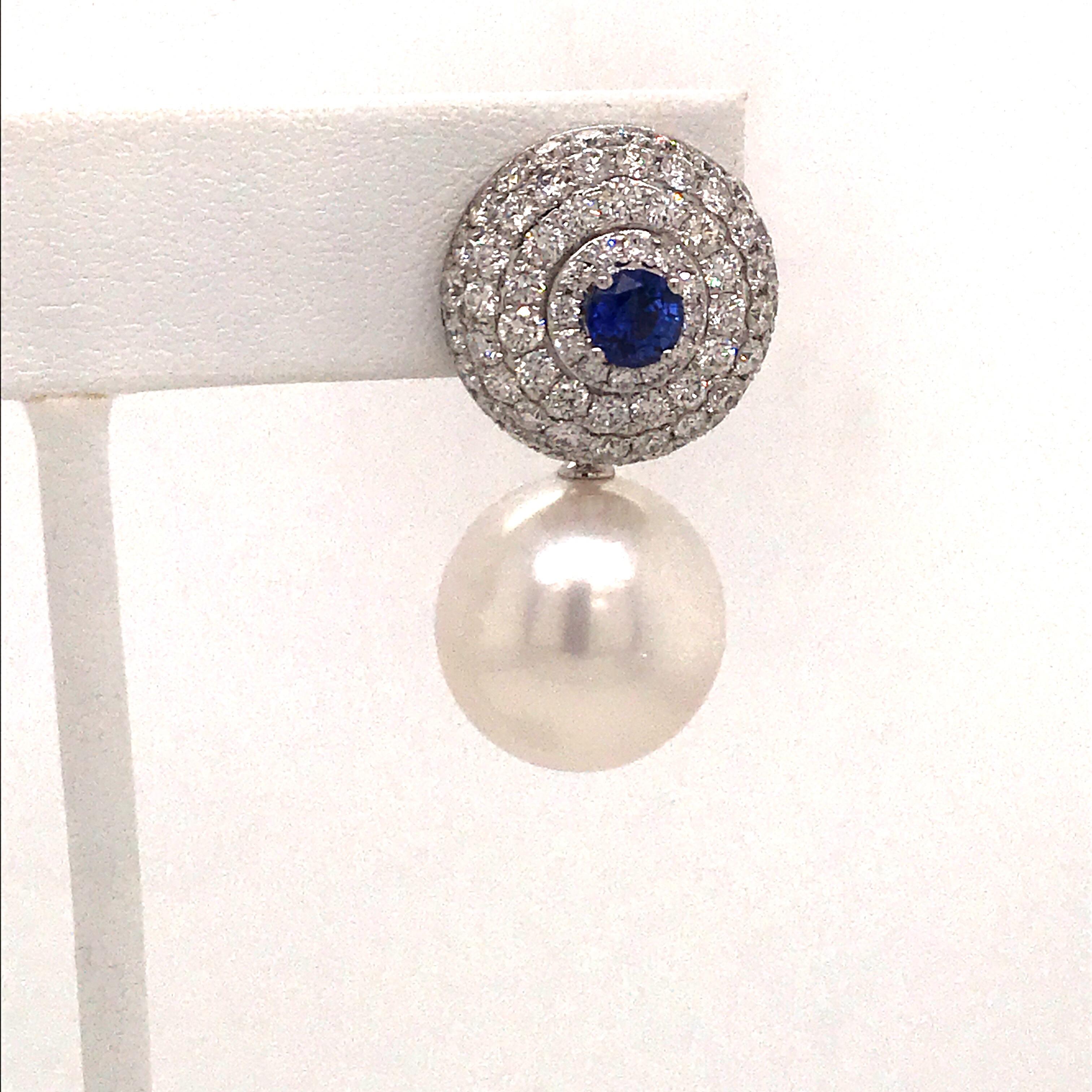 18K White gold earrings featuring 142 round brilliants weighing 3.75 carats with two center sapphires weighing 0.95 carats and white South Sea Pearls measuring 14-15 mm.