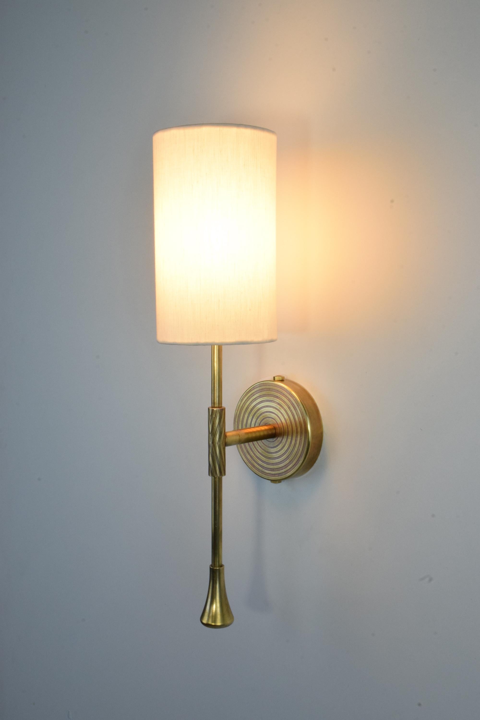 Daya is a timeless wall light built in a solid brass structure with a cylinder white fabric shade and modern hand- engravings on the wallplate and stem.
The engravings are optionable. 

Light source
1x60 W Max E14
230 V - LED Integrated 120 V -
