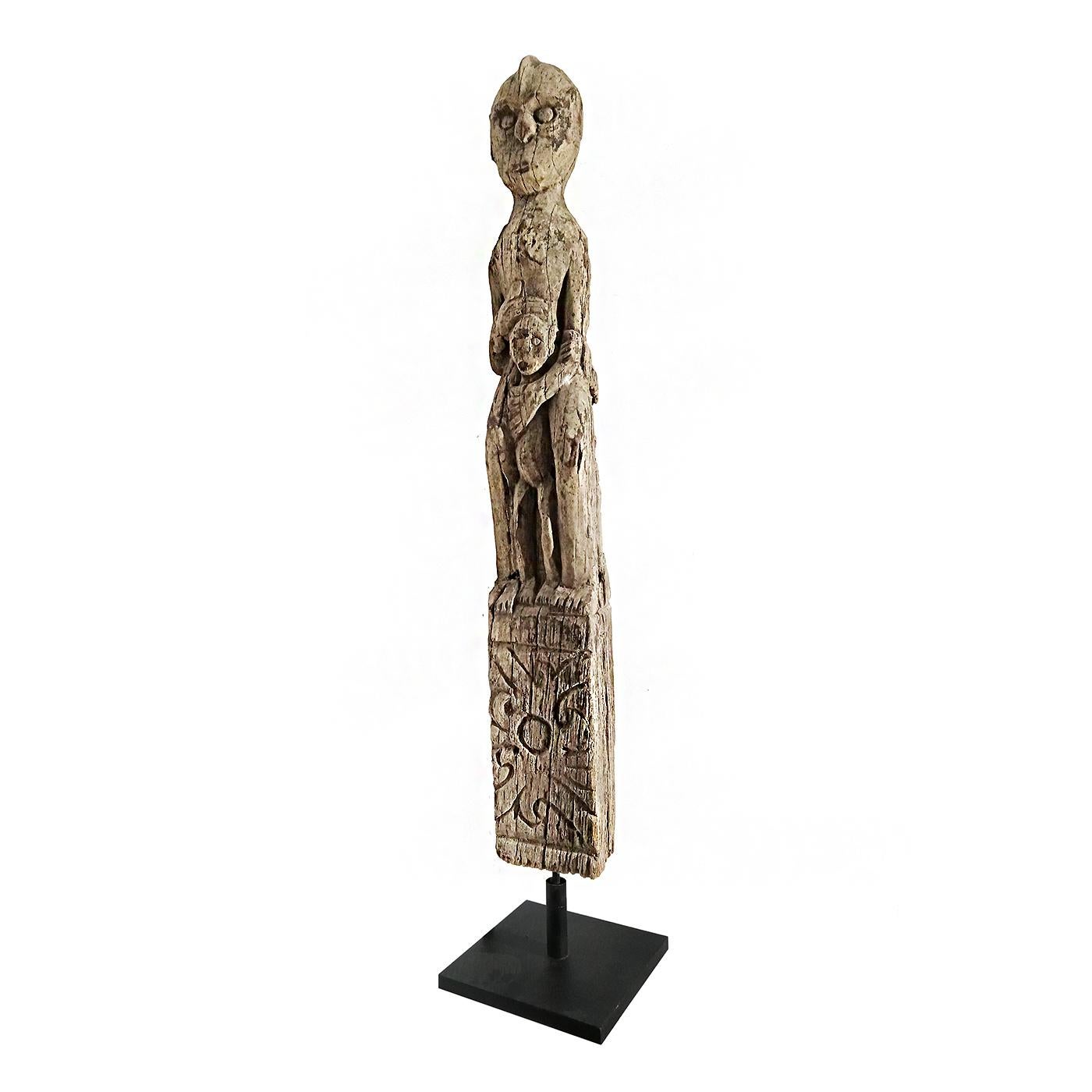 A hand-carved effigy of mother and child from the Dayak tribe in Borneo, mounted on a black metal stand. 

Ancestral figures were important in Dayak culture as a means of spiritual protection. Among the best known are anthropomorphic sculptures