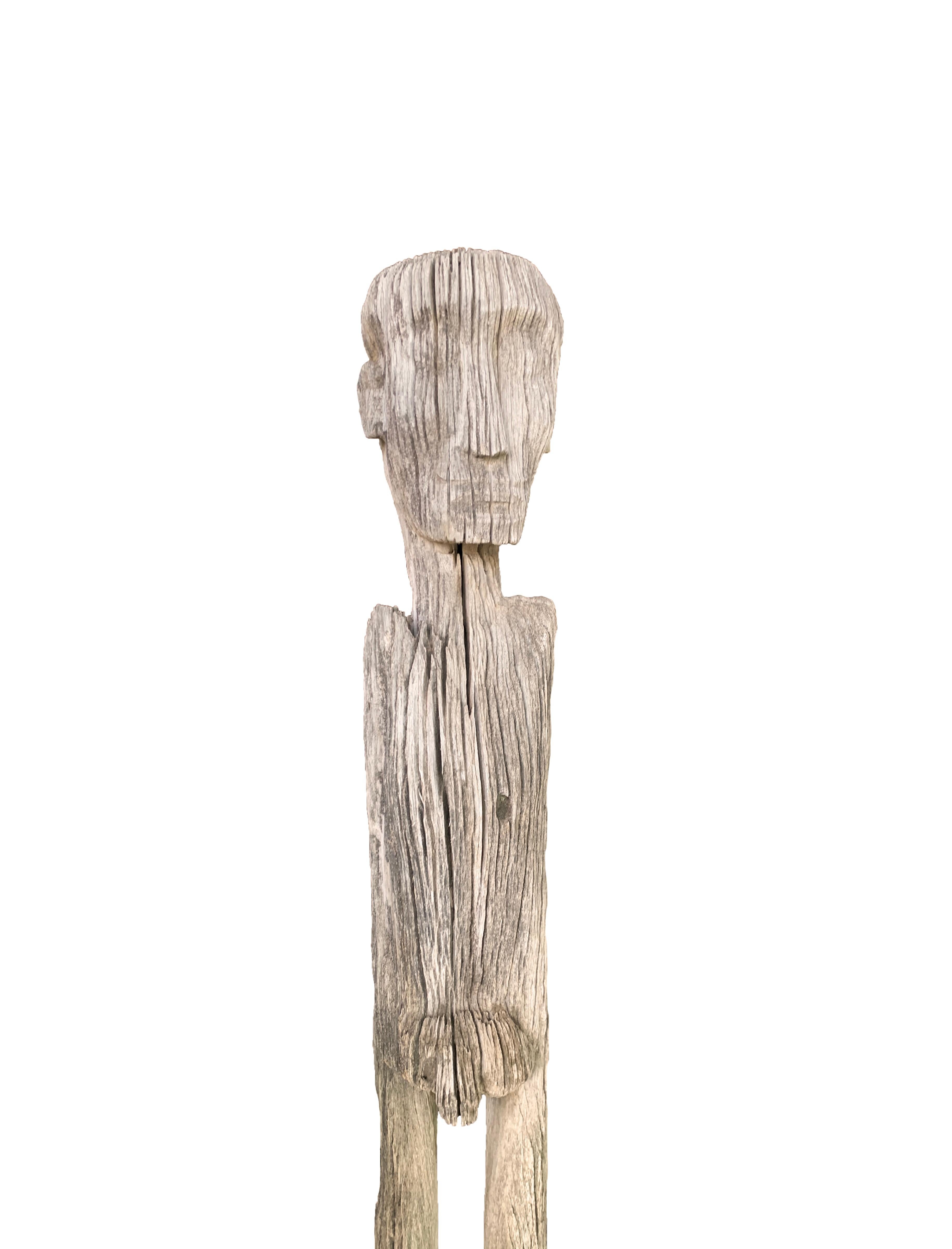 A Kalimantan carved standing sculpture of a male figure by the Dayak people from the interior rain forests of Borneo. A visibly old carving it was carved with a beautiful natural patina effect. This statue was originally used as a protective figure