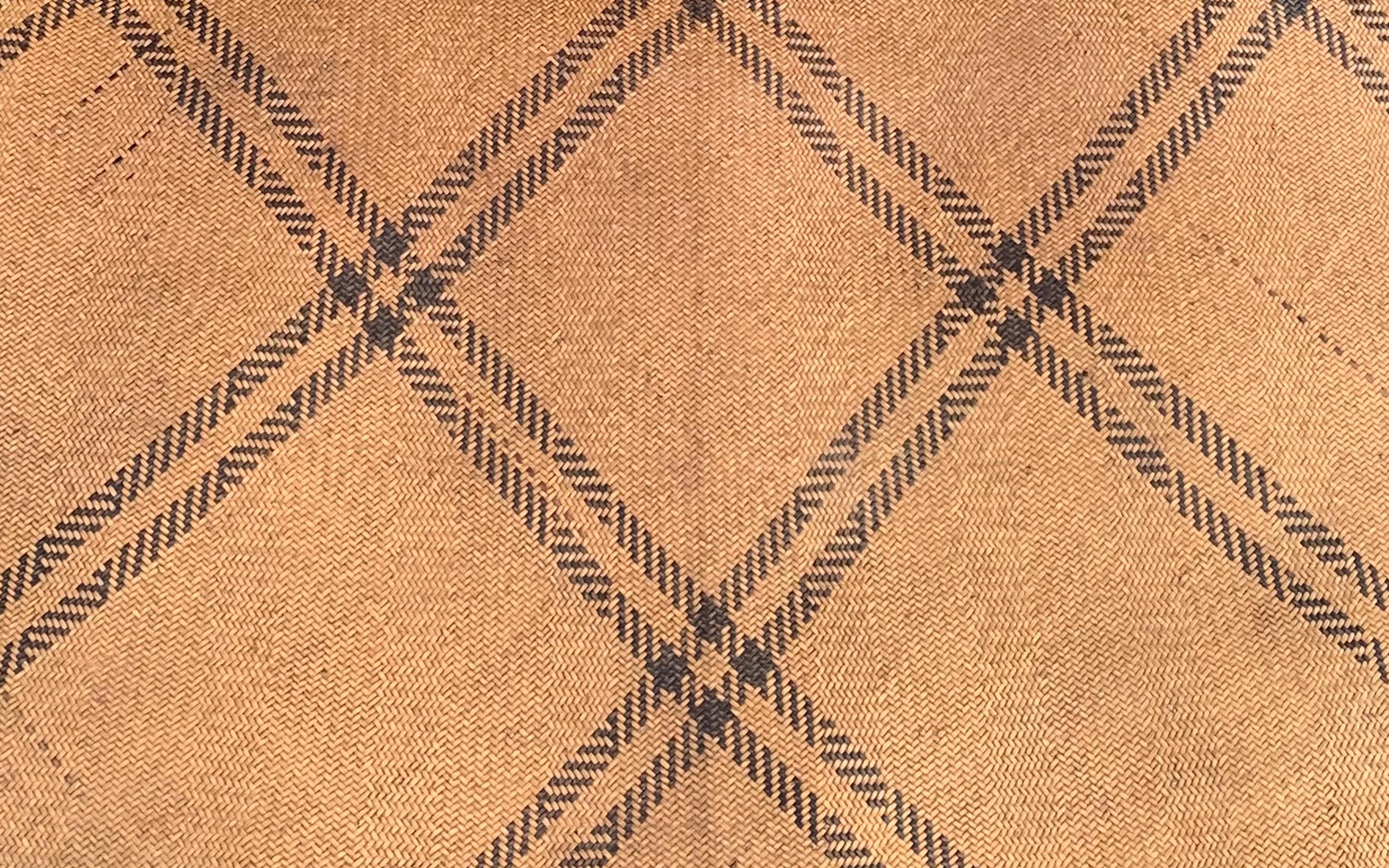 This floor mat once occupied a tribal long house of the Dayak Tribe of Borneo. It is made from woven dyed and natural coloured rattan fibres & features diagonal black fibres. 

Dimension: Height 220cm x Width 130cm.
 