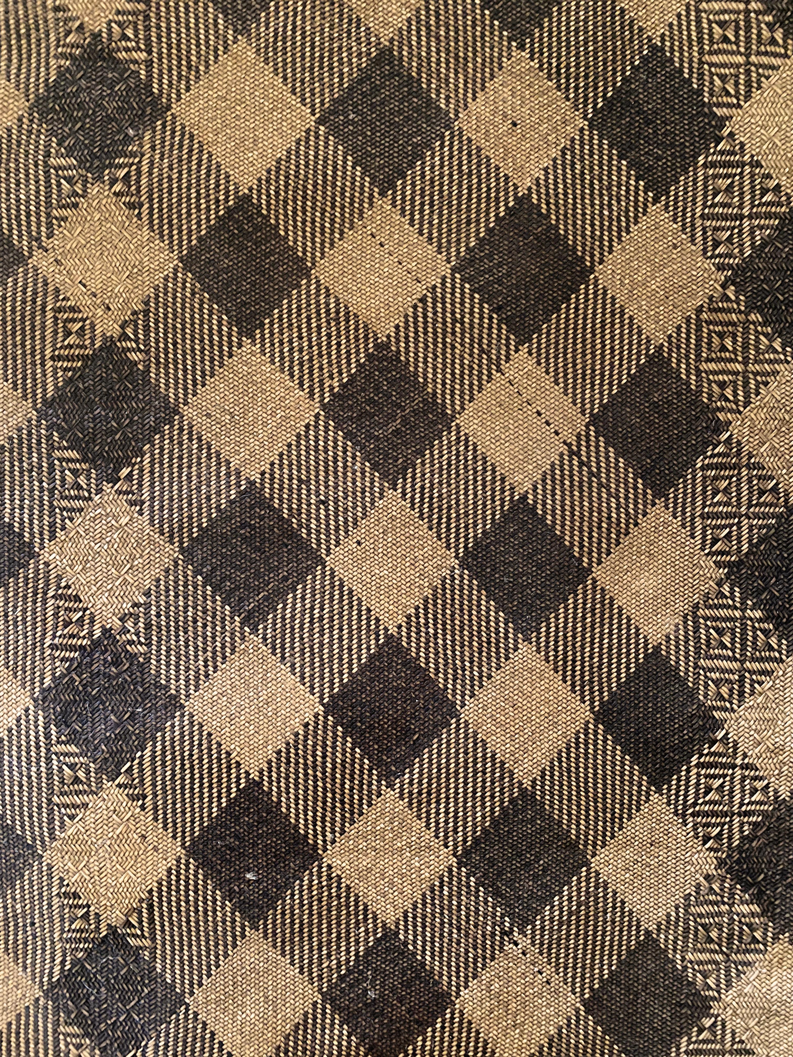 Ce tapis de sol occupait autrefois une longue maison tribale de la tribu Dayak de Bornéo. Il est fabriqué à partir de fibres de rotin tissées, teintes et de couleur naturelle, formant des motifs tribaux. Une bordure en cuir a été ajoutée au tapis.
