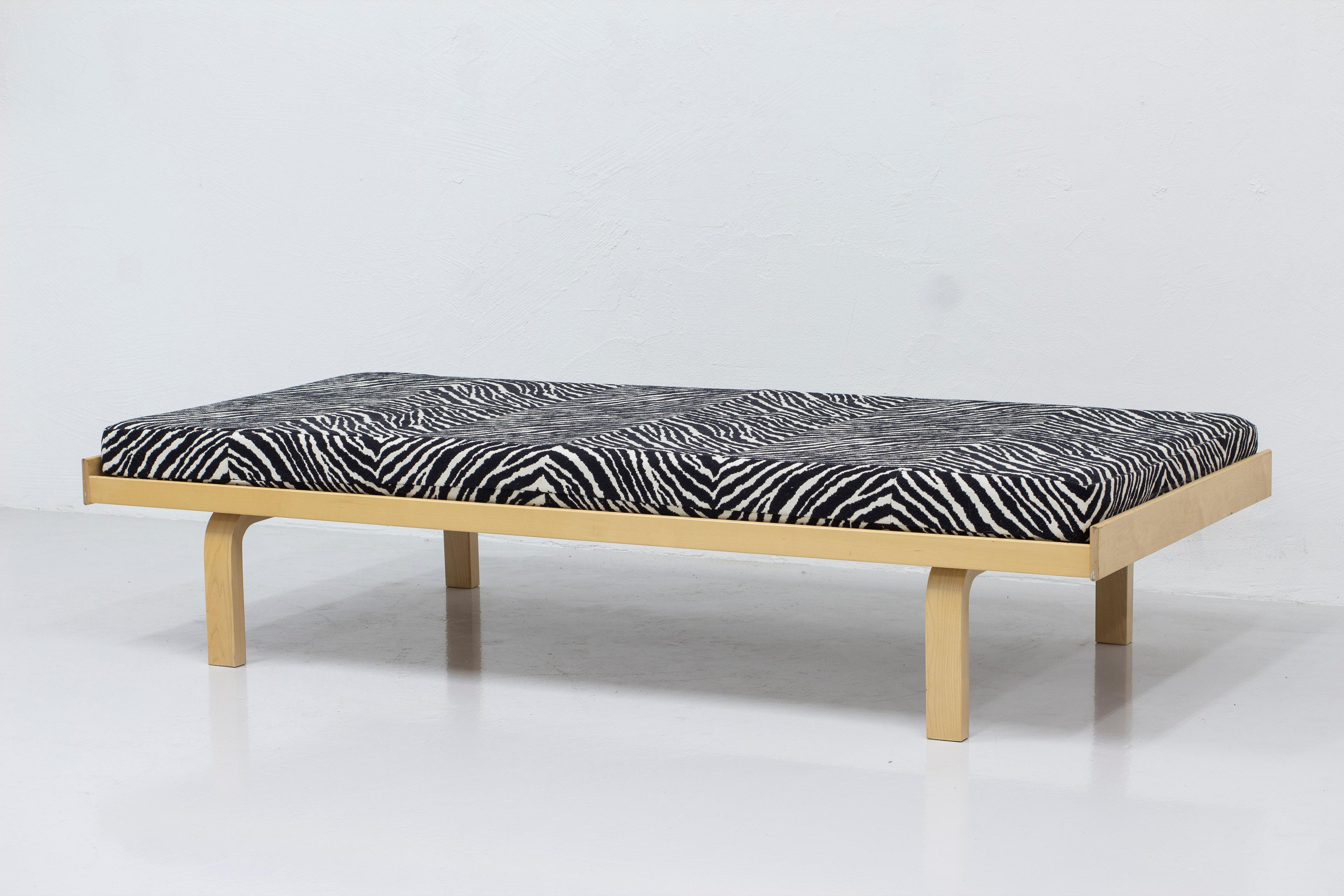 Iconic daybed model 710 designed by Alvar Aalto. Made completely from solid birch with lacquer finish. The mattress is upholstered in the iconic zebra fabric designed by Bauhaus designer Otti Berger. The fabric was hand picked by Aino Aalto in 1935