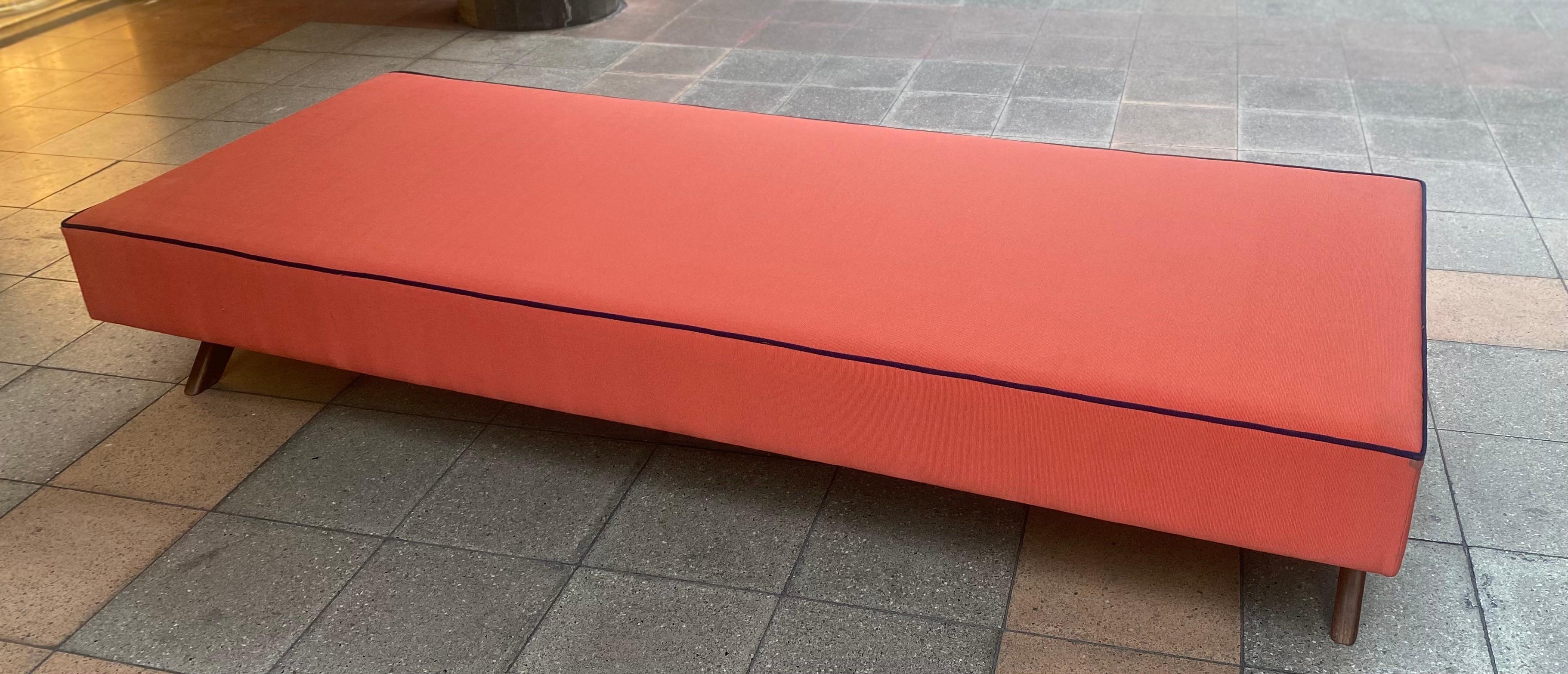 Daybed by Jeanneret 
daybed in solid teak and cotton canvas. 
Rectangular base upholstered in coral red cotton canvas with blue piping. 
circa 1957-58.
Dimensions: 
Height: 37 cm.
Length : 197 cm.
Width: 79 cm (+/-).
Origin France 
attribution mark