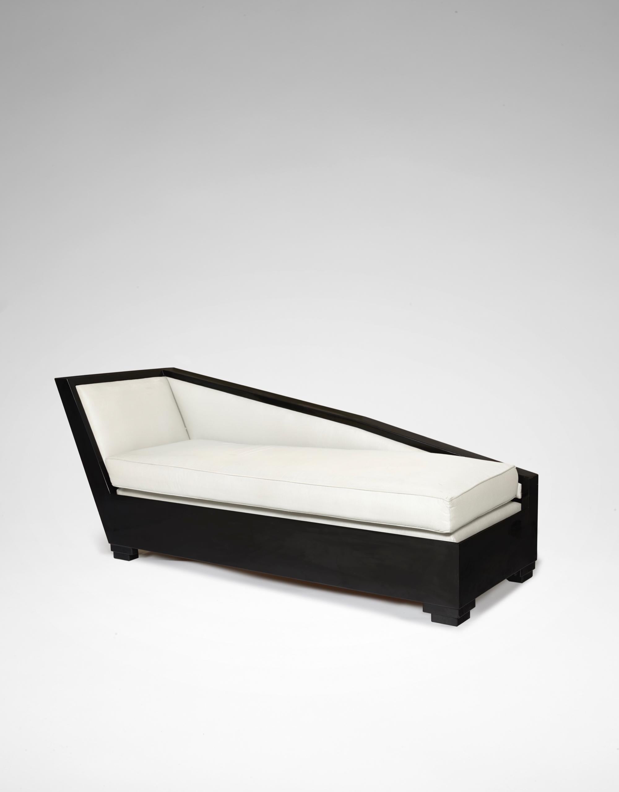 A Black lacquered wood daybed, small feet, covered with ivory colored fabric.